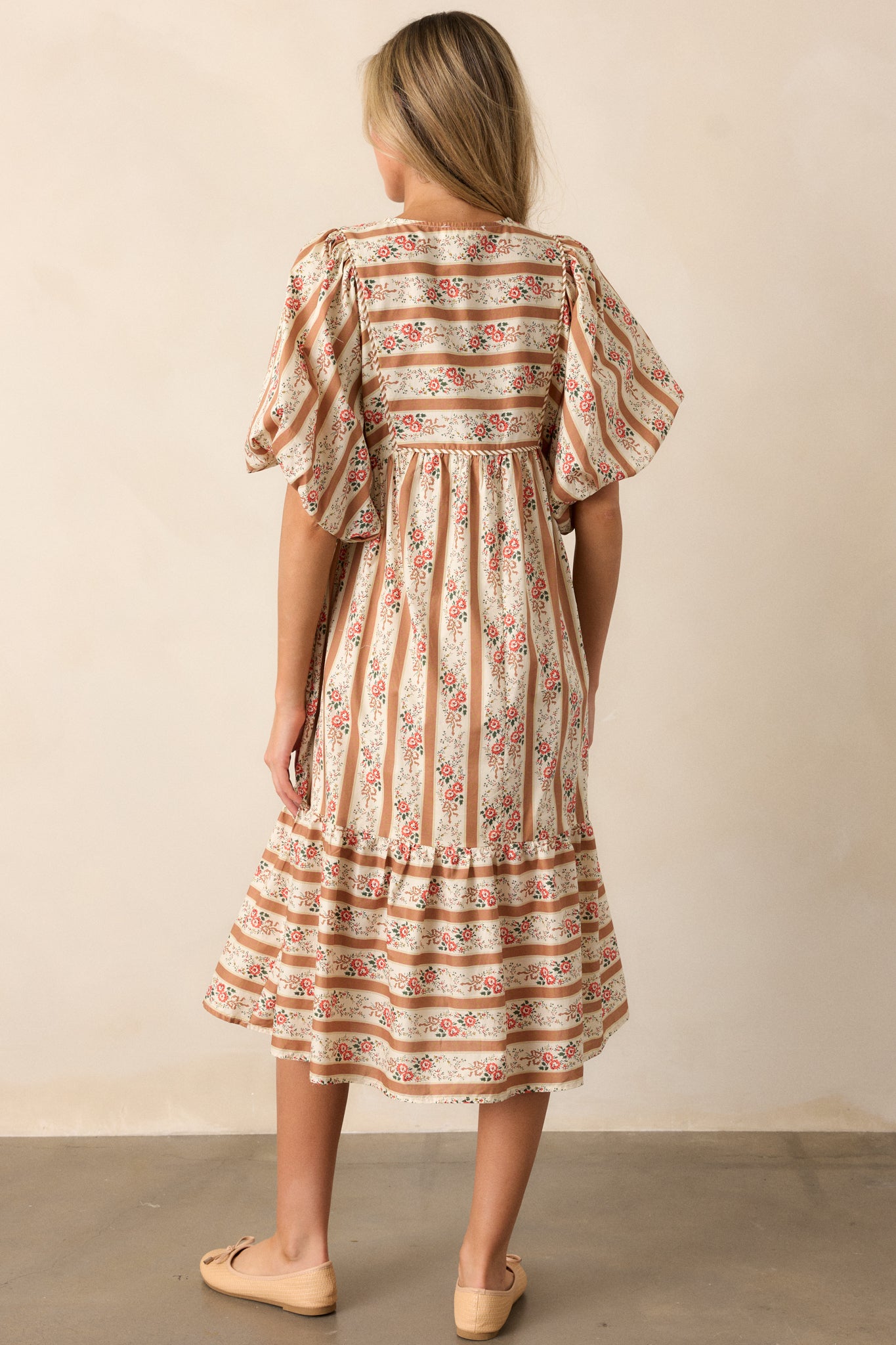 A rear view of the dress, displaying the mix-matched pattern and the midi length from the back, with a view of the puff sleeves