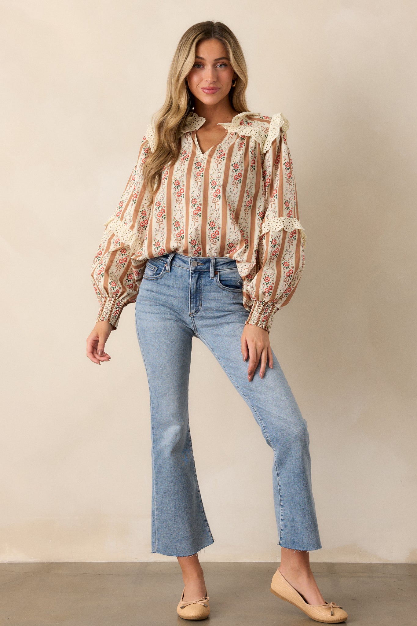 A full-length view of the camel blouse, showcasing the v-neckline and the mix of stripe and floral patterns throughout the garment.