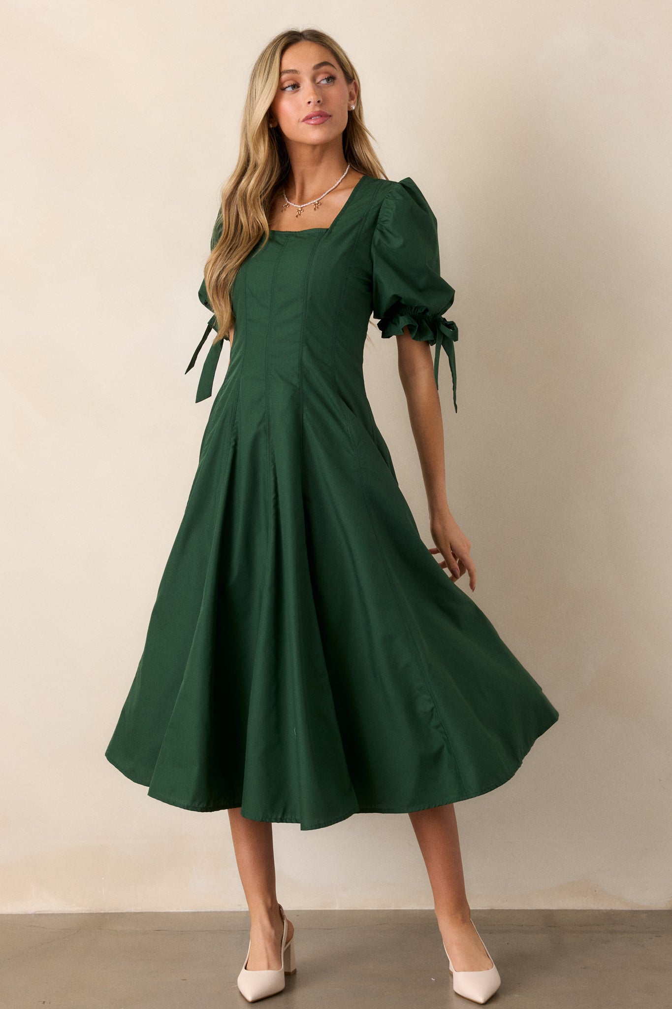 A three-quarter angle of the green dress, focusing on the puff sleeves with bow accents and the soft, flaring midi-length hem.