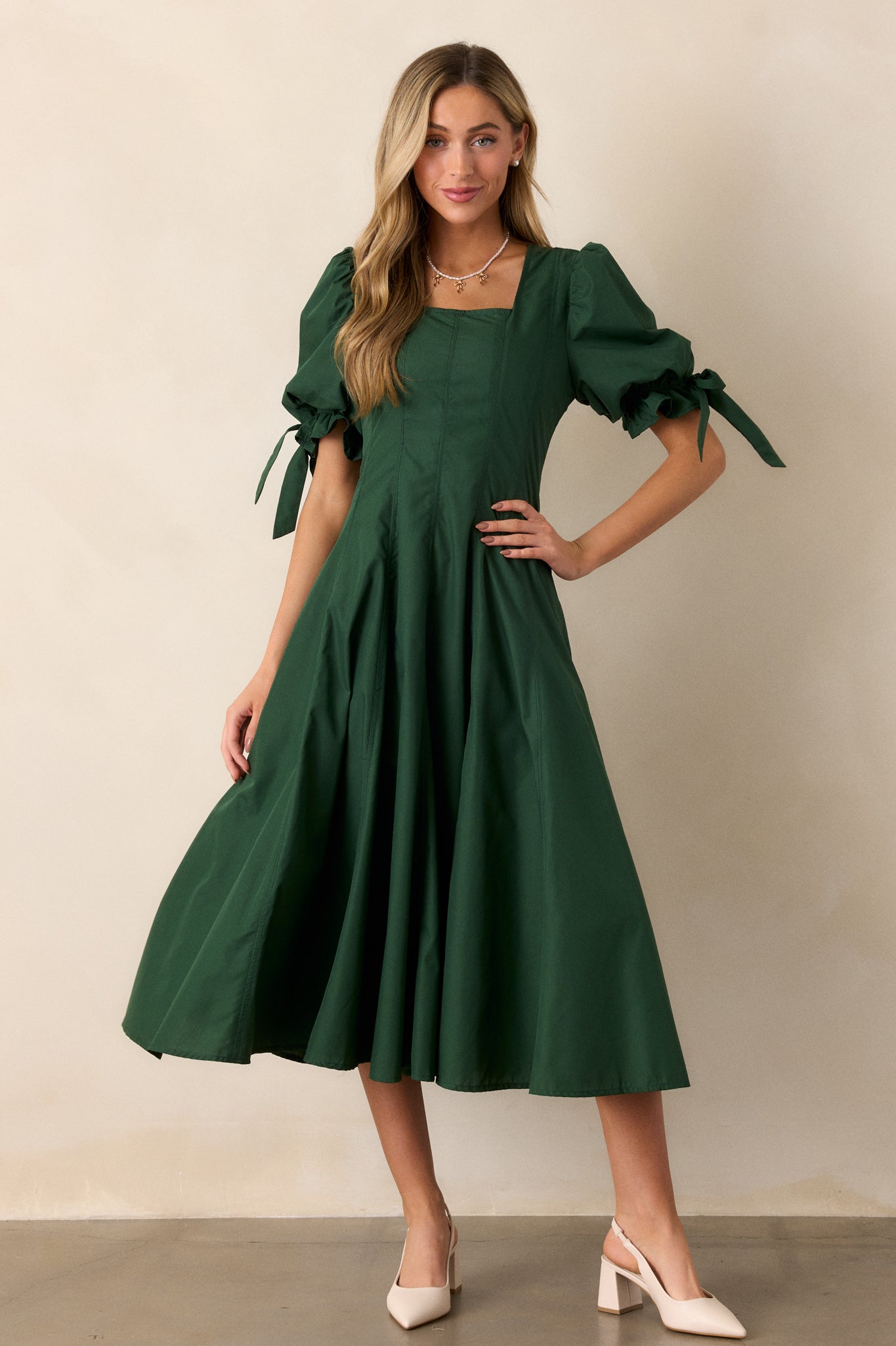 A front-facing view of the green dress, highlighting the fit-and-flare design, square neckline, and the puff sleeves with bow details.