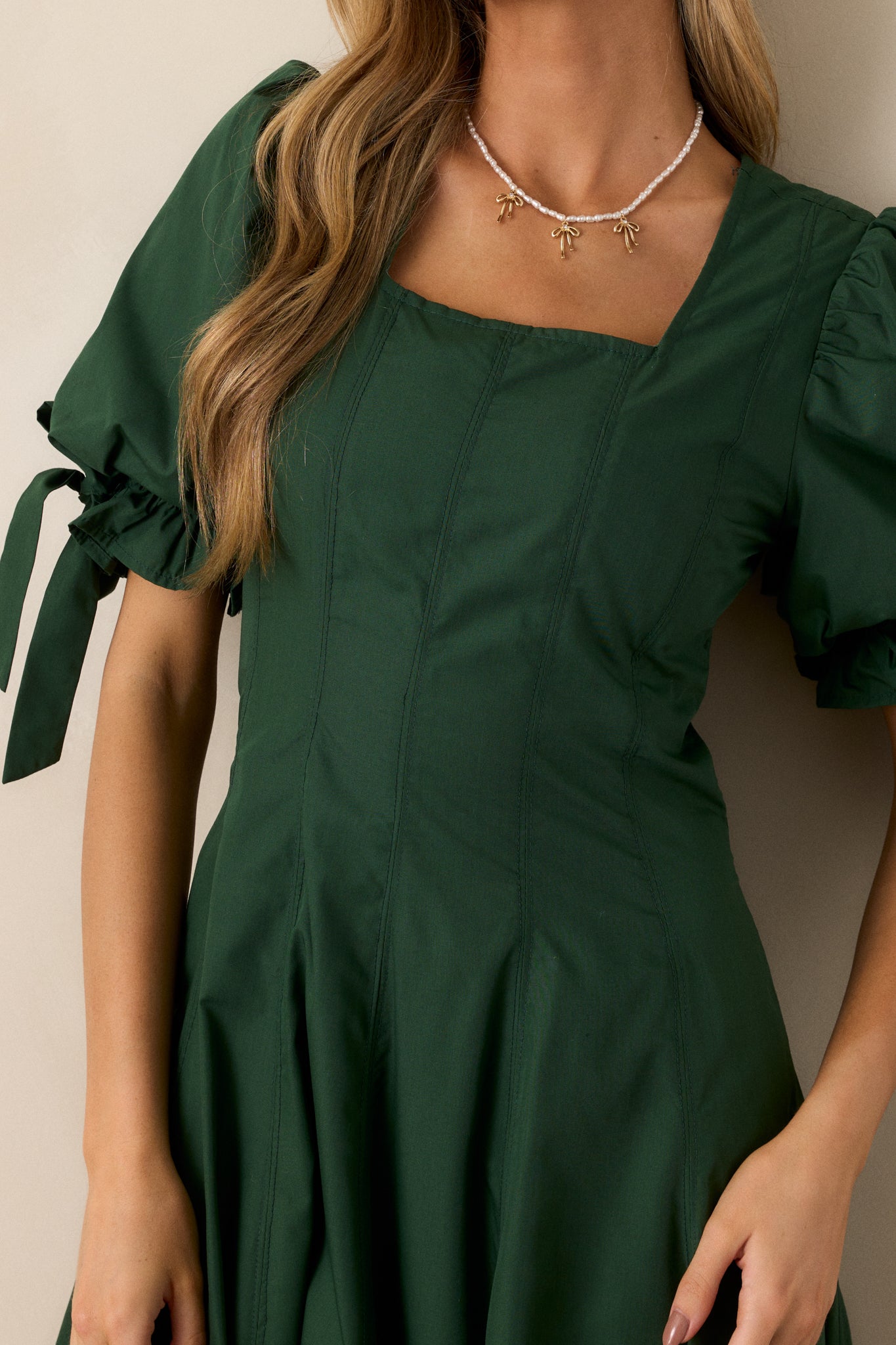 A close-up of the puff sleeves on the green dress, focusing on the smocked detailing and the bow accent.