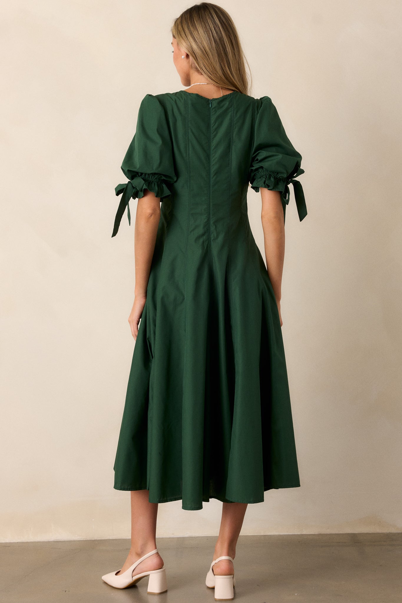 A back view of the green dress, showcasing the discrete back zipper and vertical seam details running down the dress.