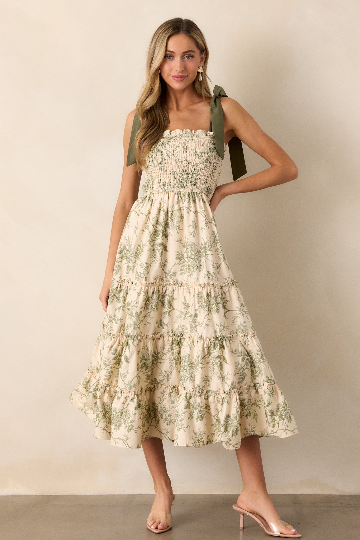 The ivory dress with green floral details, shown from a three-quarter angle, emphasizing the smocked bodice and flowing skirt.