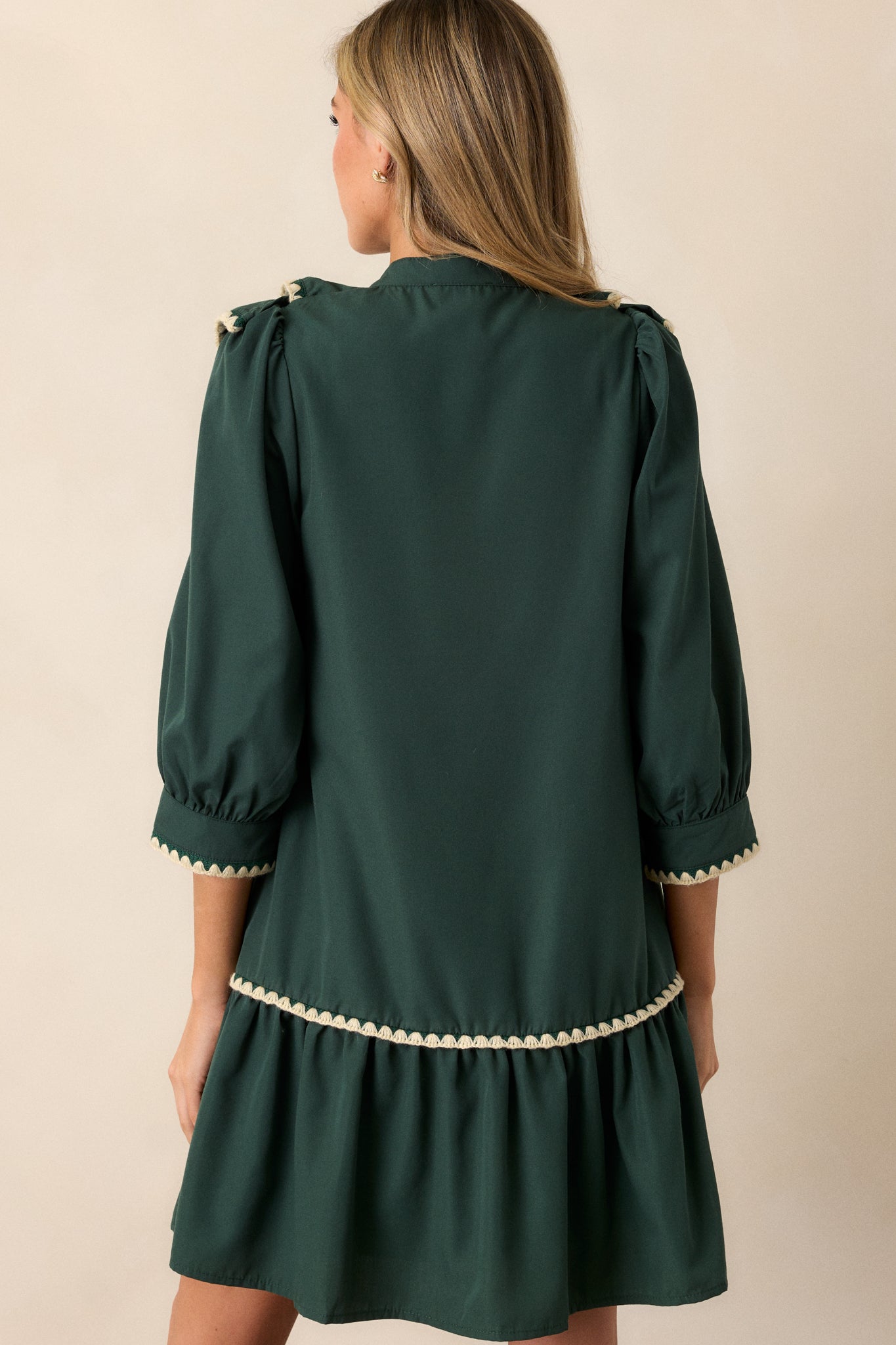 A back view of the green dress, highlighting the tiered skirt and the elegant design of the 3/4 length sleeves.