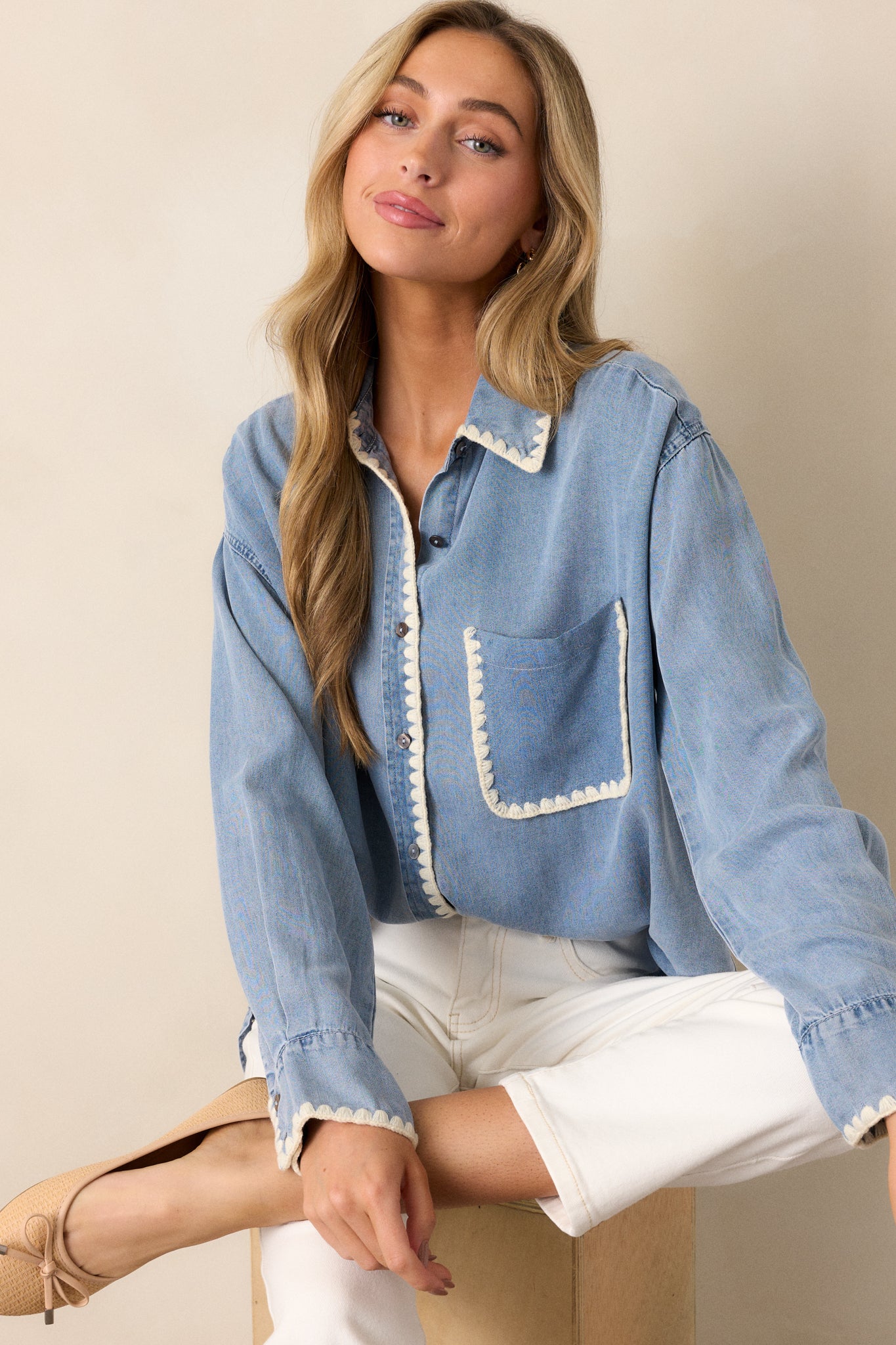 Angled view of the light wash chambray top, showcasing the functional button front, long sleeves, and smooth drape of the fabric.