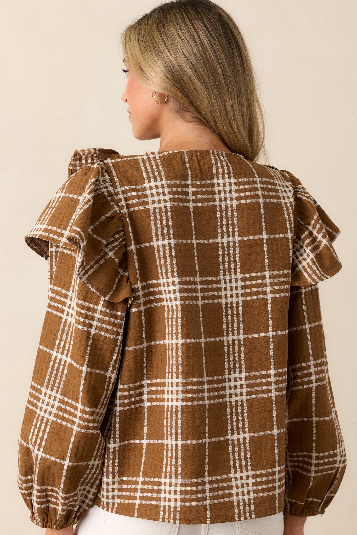 View of the back of the blouse, featuring the continuous plaid pattern, the boxy fit, and the subtle puff of the sleeves from behind.