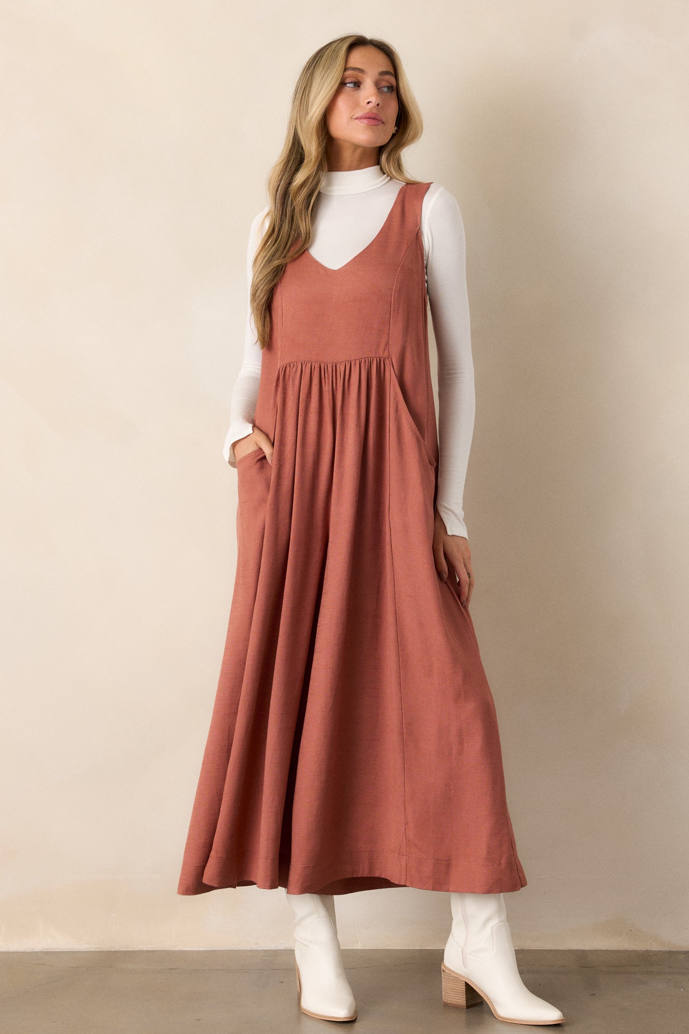 A full view of the terracotta jumpsuit from the front, showcasing the v-neckline and sleeveless design, highlighting the flowy wide legs that create an elegant silhouette.