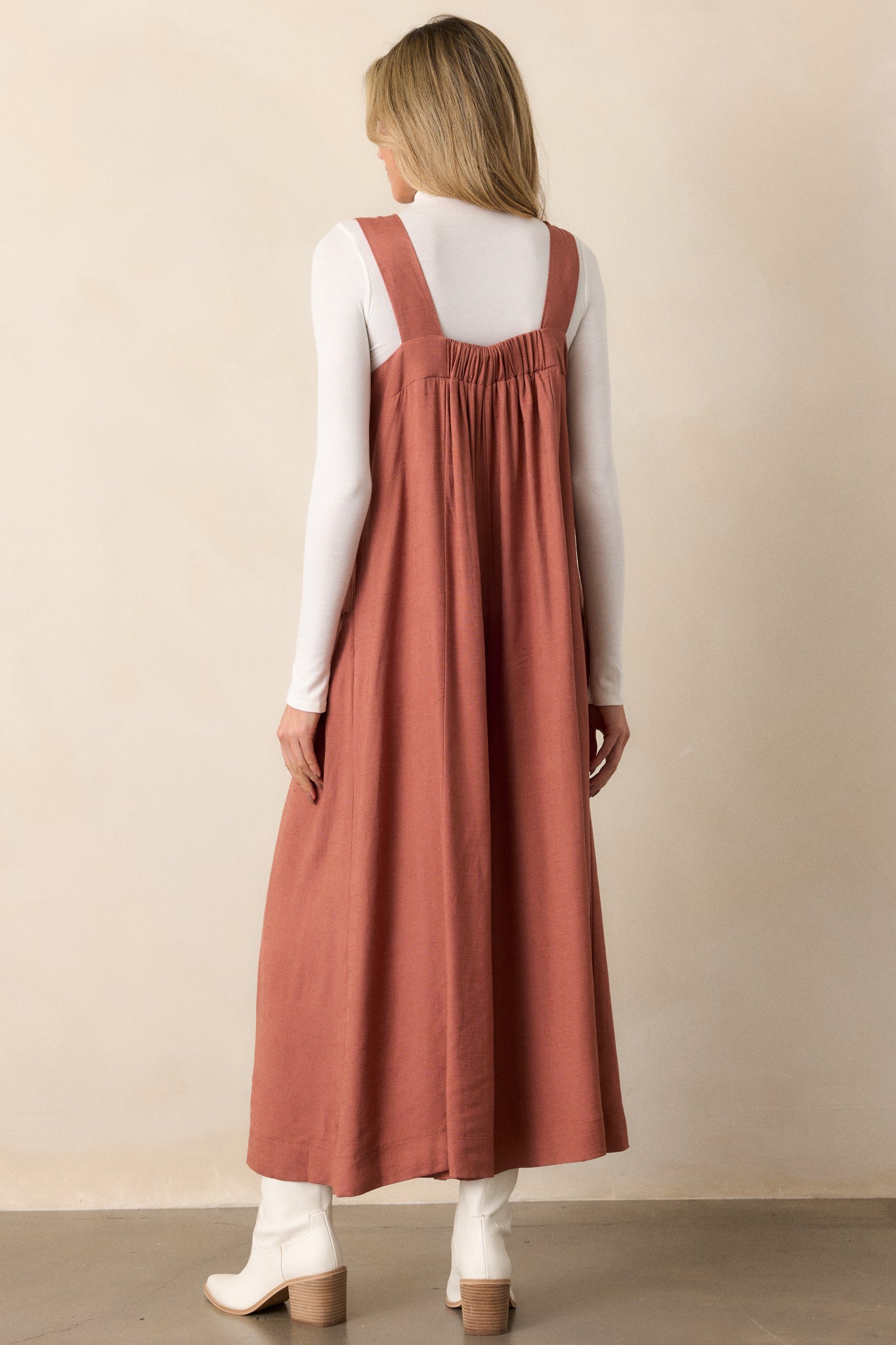 A back view of the jumpsuit, highlighting the clean lines and fit, emphasizing the design's simplicity while showcasing how it drapes from the shoulders down to the wide legs.