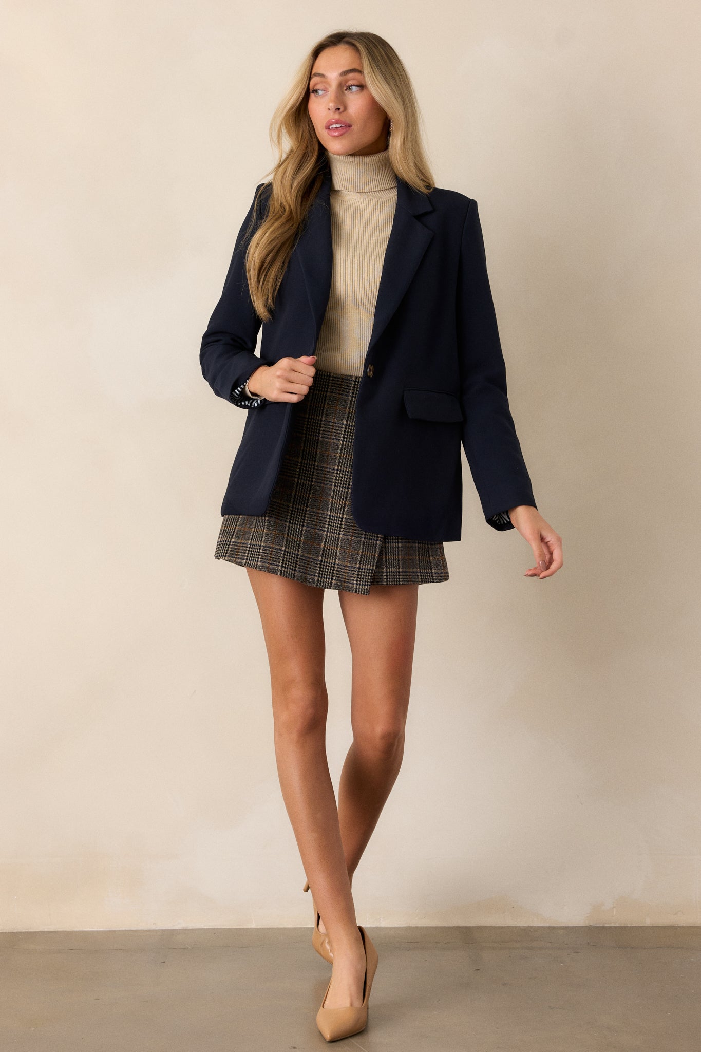 Model walking in this navy blazer featuring a collared neckline, a middle button closure, padded shoulders, a floral lining and long sleeves.