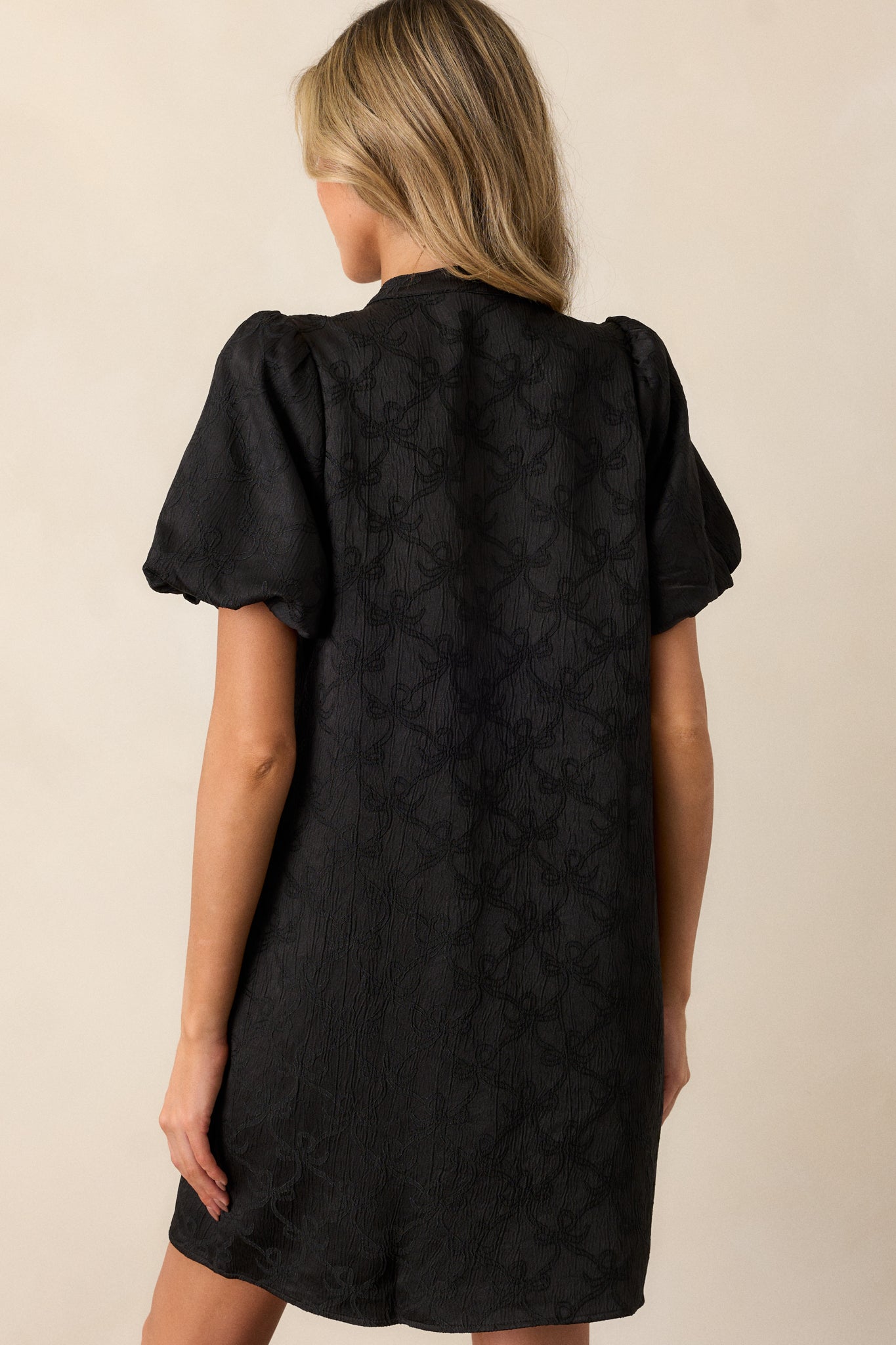 A rear view of the dress, displaying the continuation of the bow pattern and the elegant puff sleeves that frame the shoulders.