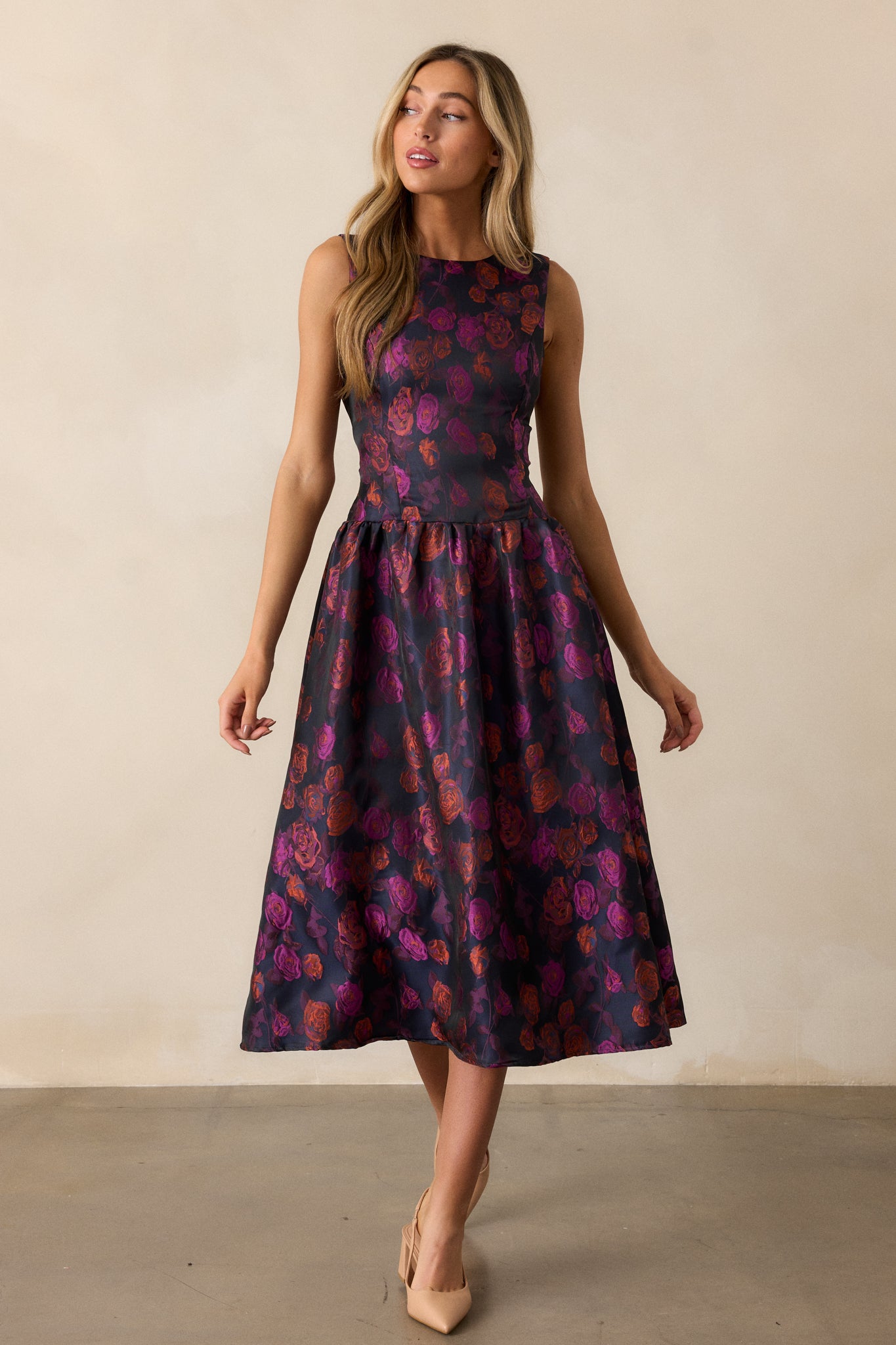 A full view of the purple dress with a floral design, emphasizing the high rounded neckline and the flattering sleeveless style.