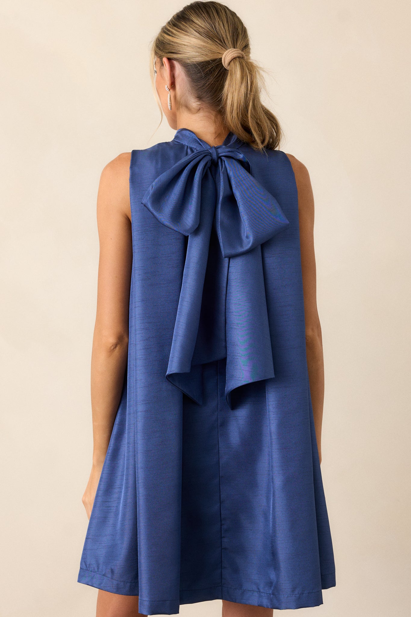 The back of the royal blue dress featuring a high neckline and self-tie bow, illustrating the elegant simplicity of the shift silhouette.