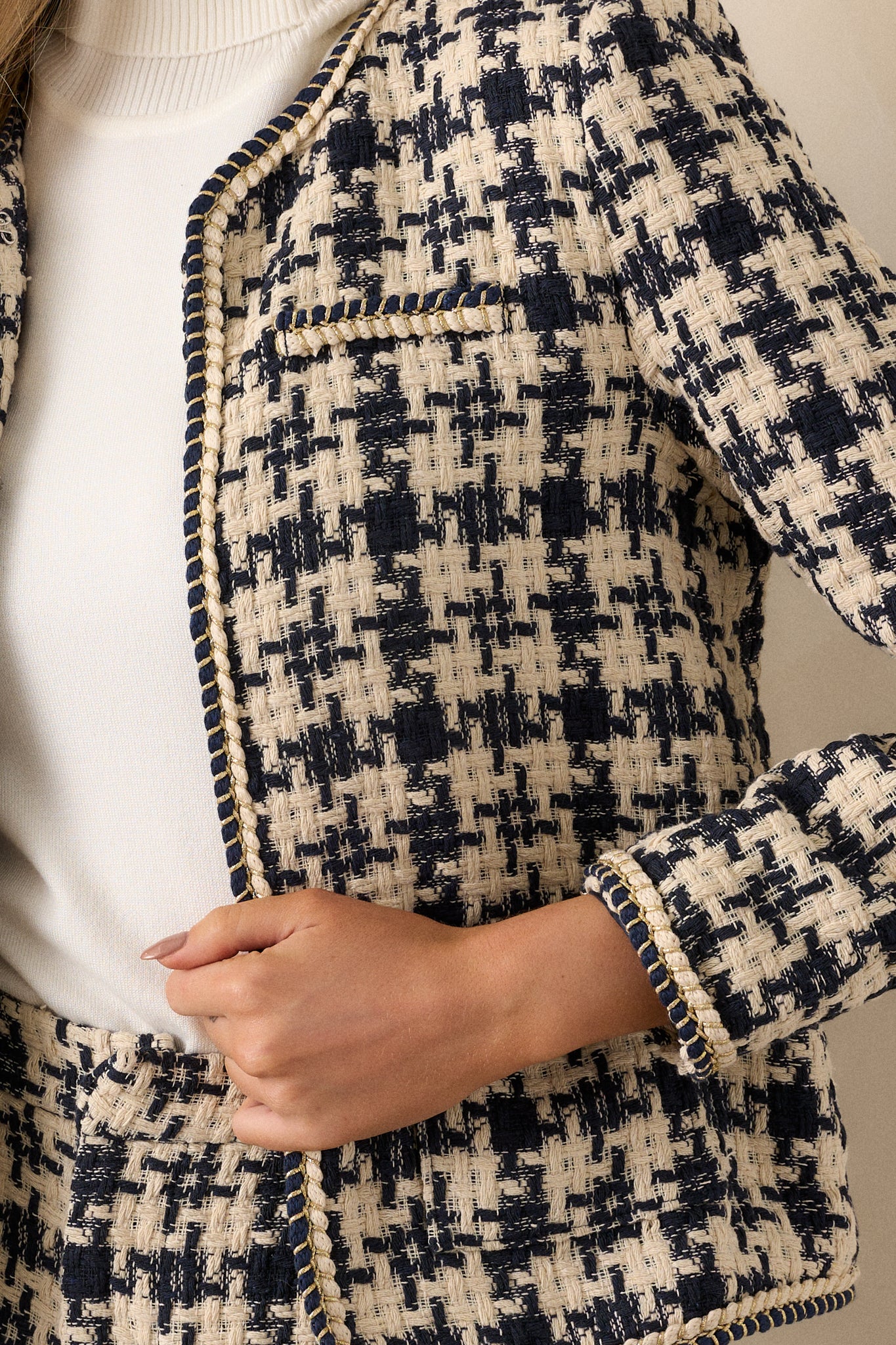 A close-up of the gold rope twist trim on the front of the navy tweed jacket, highlighting the intricate detailing and texture of the fabric.