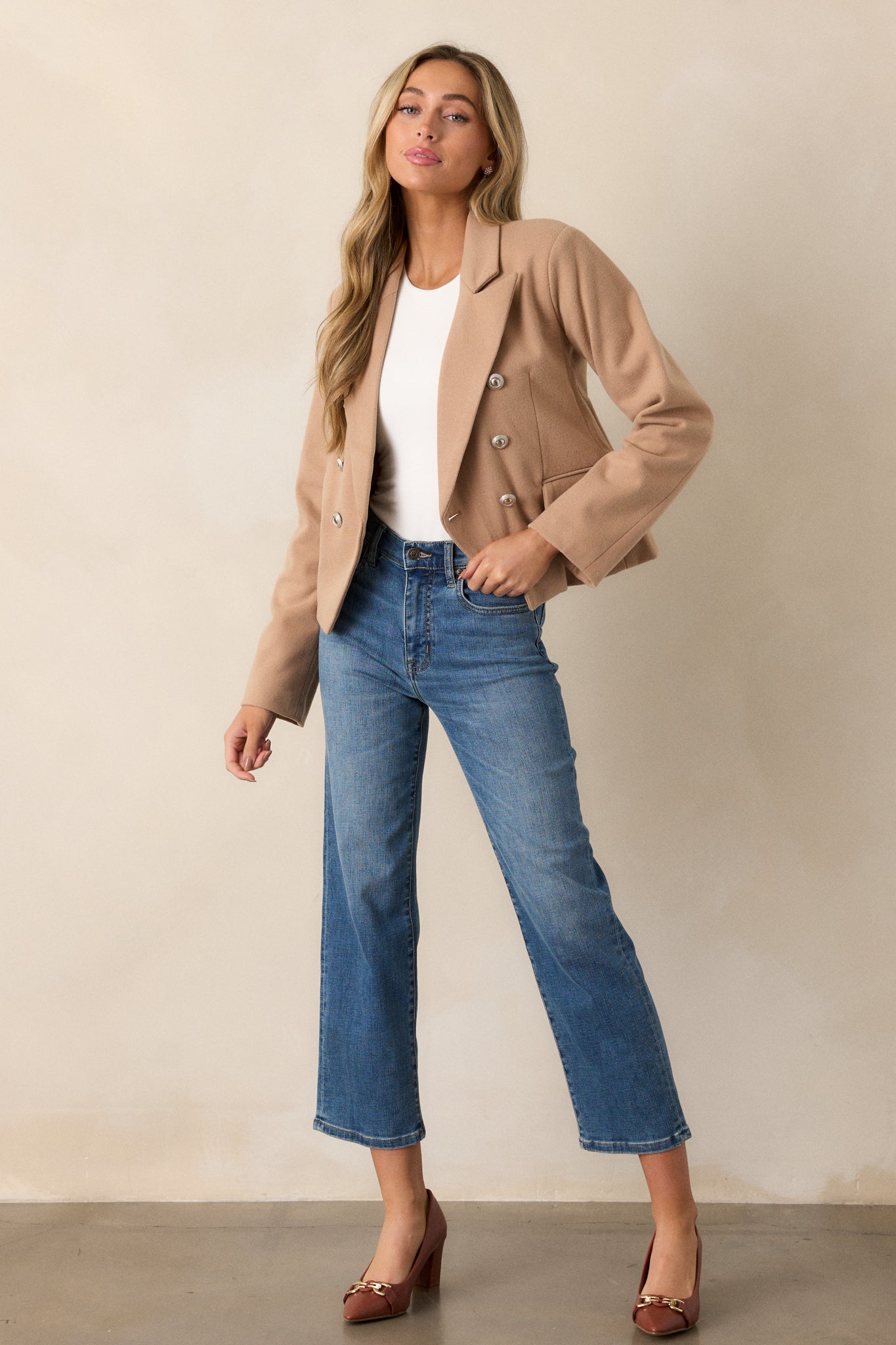 A full-length view of the tan blazer, highlighting its cropped boxy fit and long sleeves.