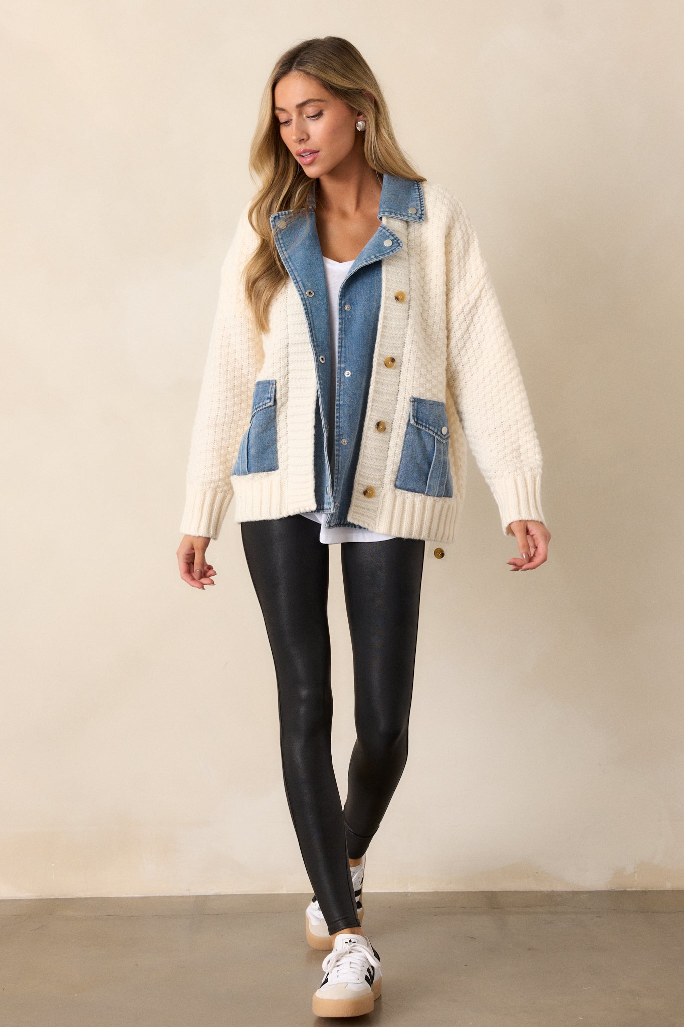 A full-body shot of the jacket, emphasizing the ivory knit mock sweater overlay, blue denim mock undershirt, and brown detail buttons down the front.