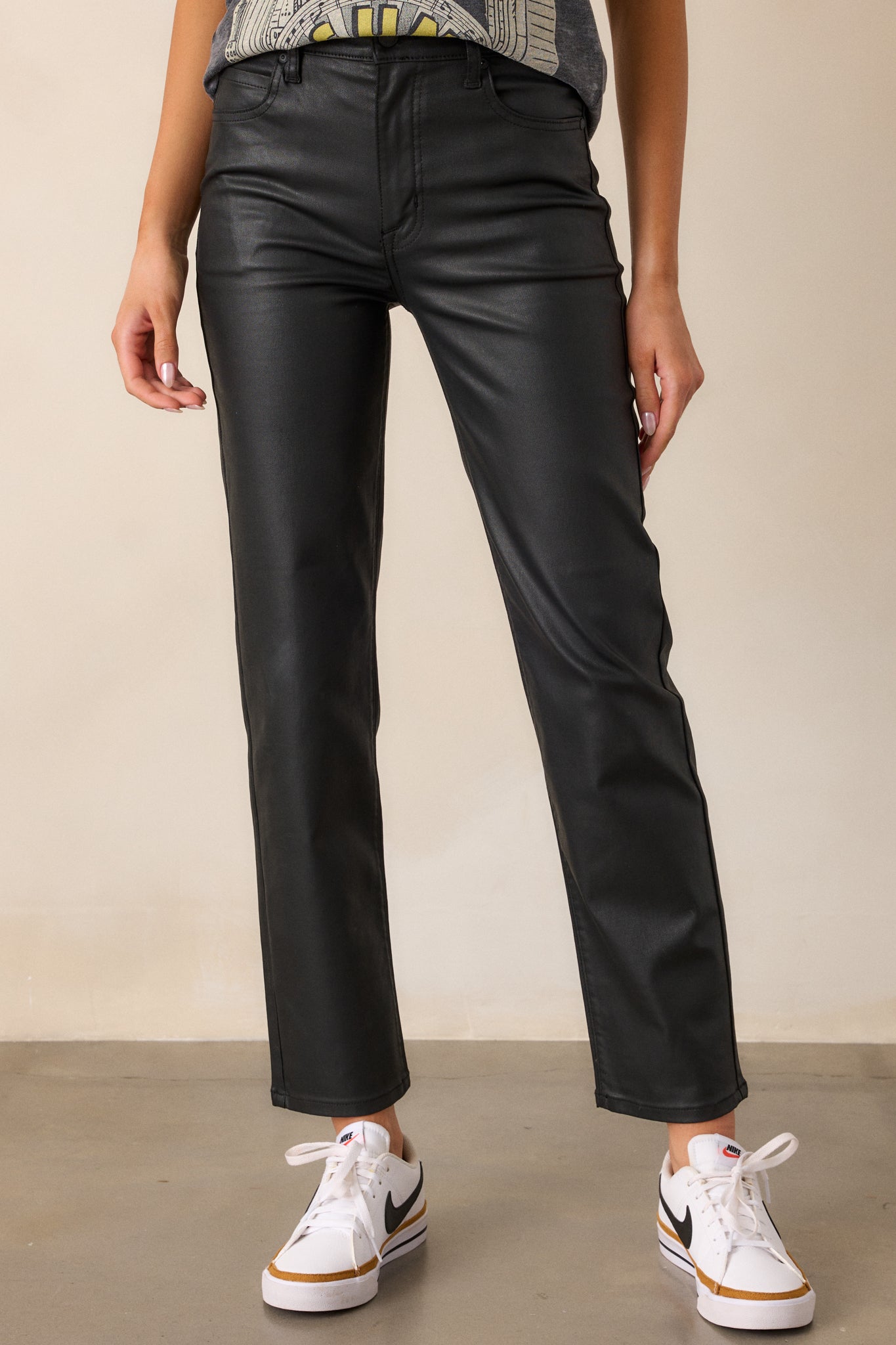 Close-up of the high-waisted waistband and front button-zipper closure, showing the smooth faux leather texture.