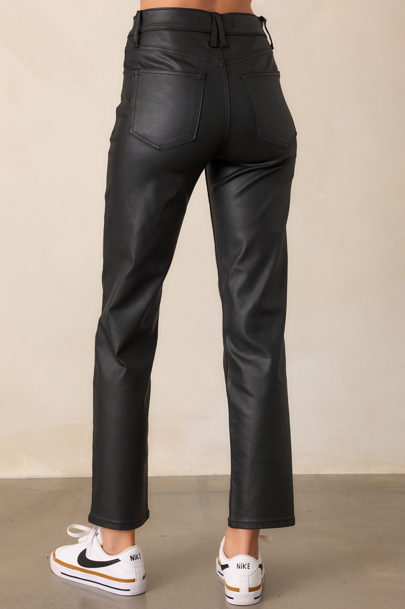 View of the back, highlighting the two functional back pockets and the straight leg cut in black faux leather.