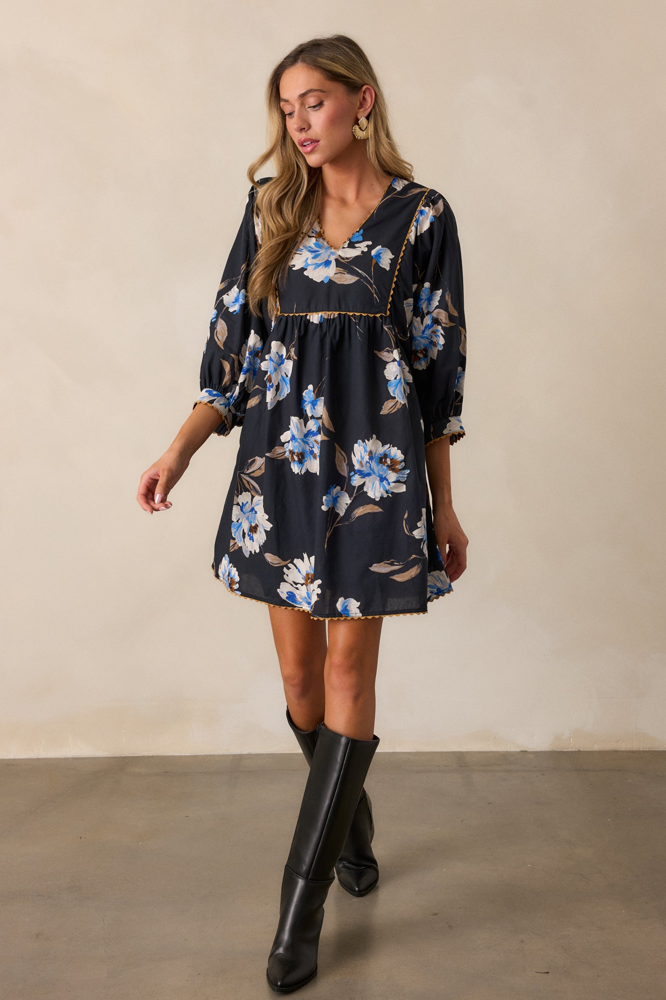 Black dress with a v-neckline and mini length, highlighting the blue and white floral pattern and tan stitching on the 3/4 sleeves.