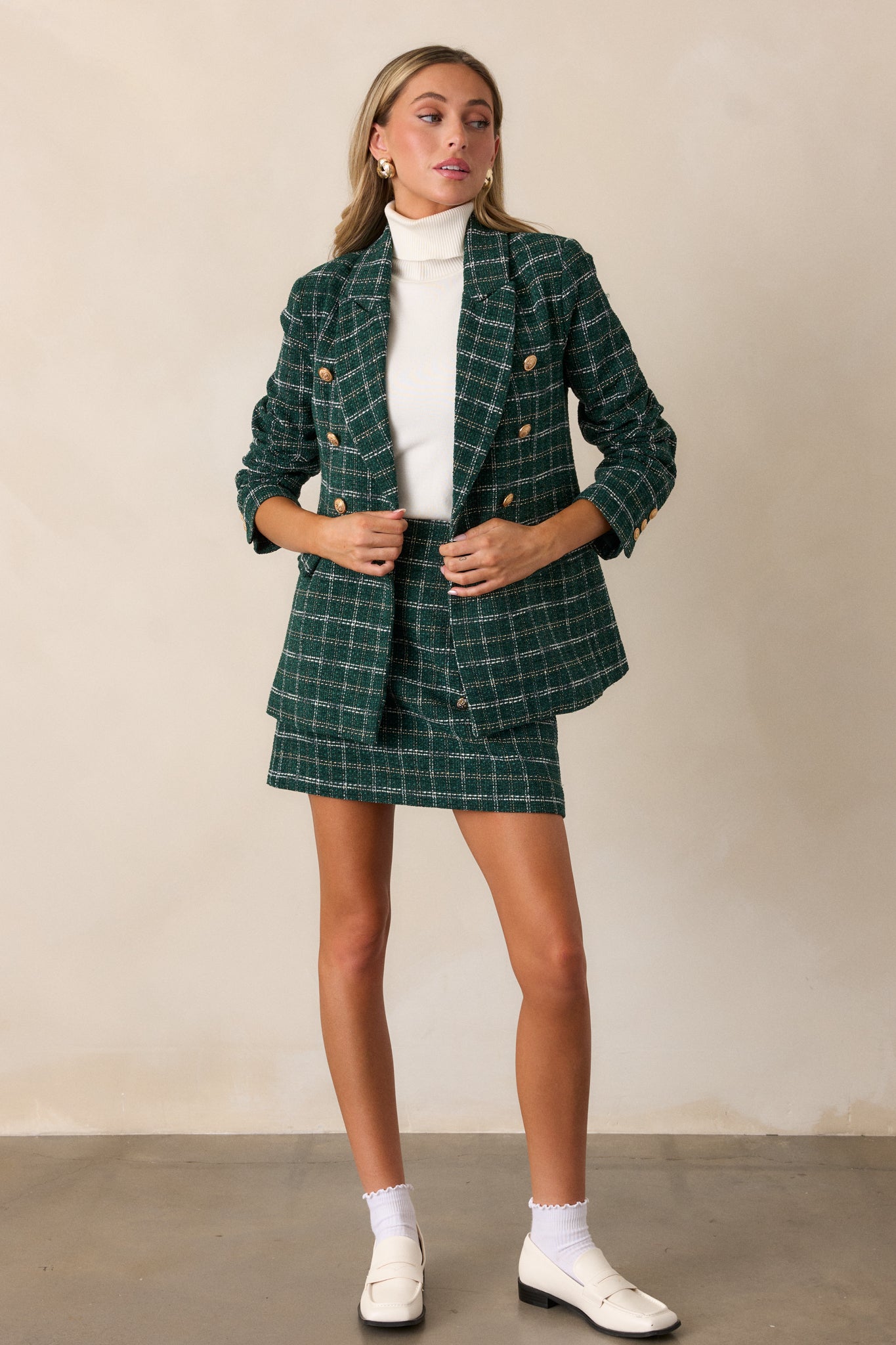 Another full body shot of the forest green mini skirt, showcasing the fitted silhouette and rich tweed texture with subtle gold and white stitching.