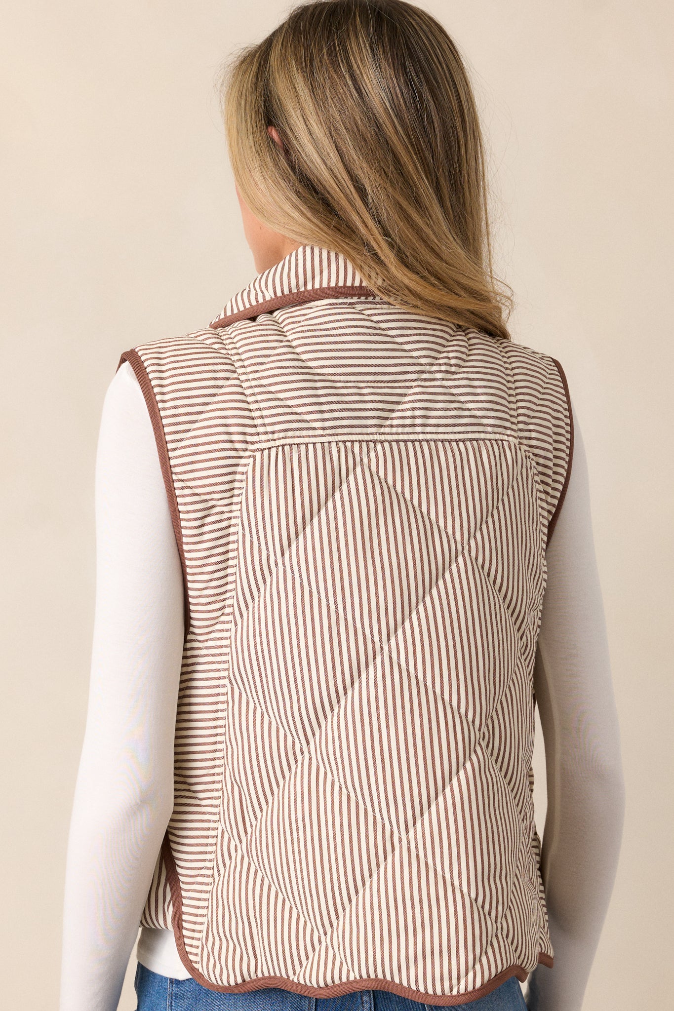 Back view of the chocolate vest, showing the quilted stripe pattern throughout and brown knit hems along the sides and wavy bottom seam.