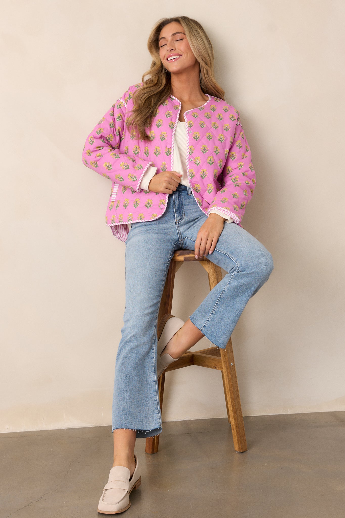  A pink jacket with a floral pattern, long sleeves, and stripe trim, shown styled for a casual and versatile look.