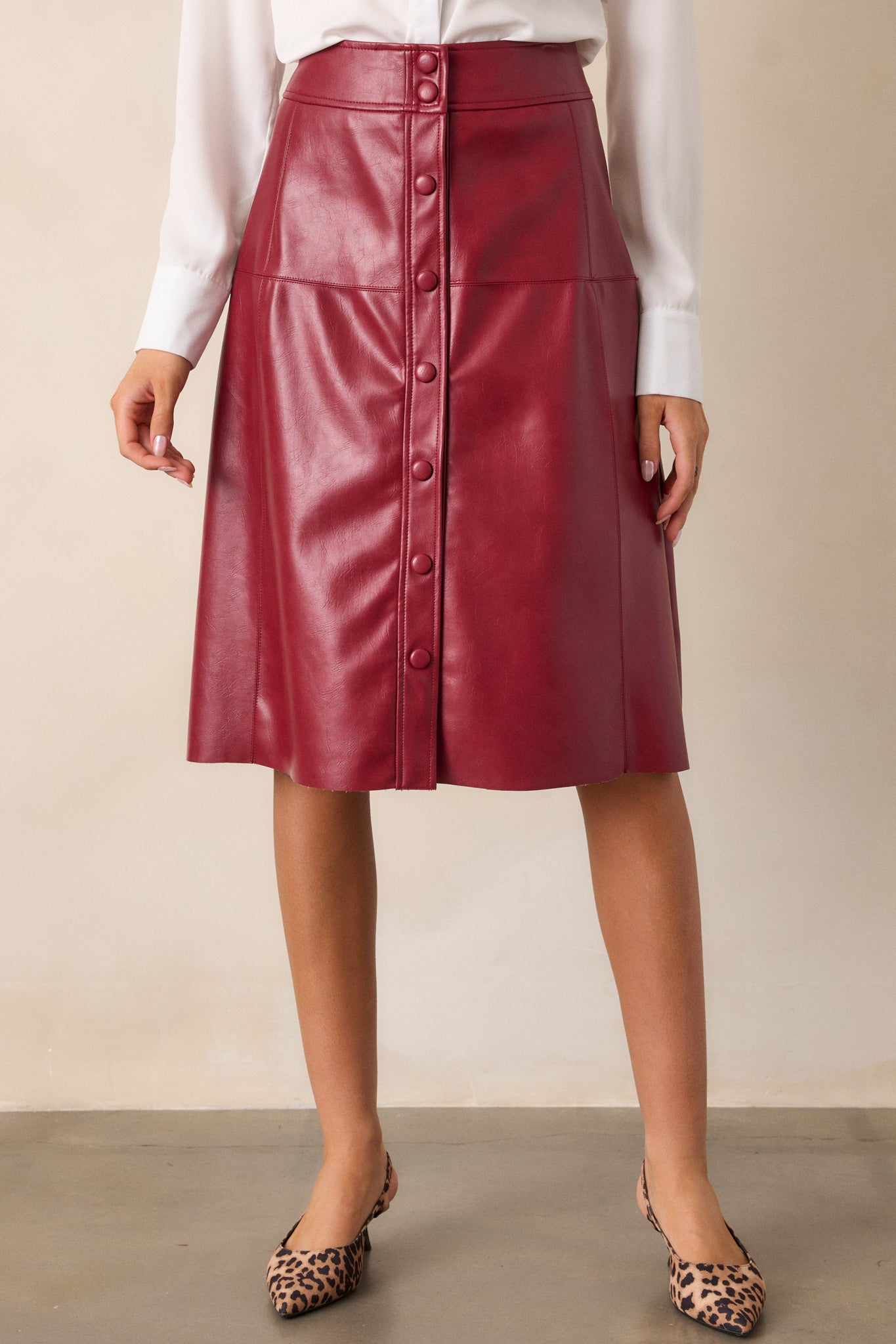 Angle showing the burgundy skirt’s smooth faux leather fabric and subtle shine, with a focus on the snap button closure area.