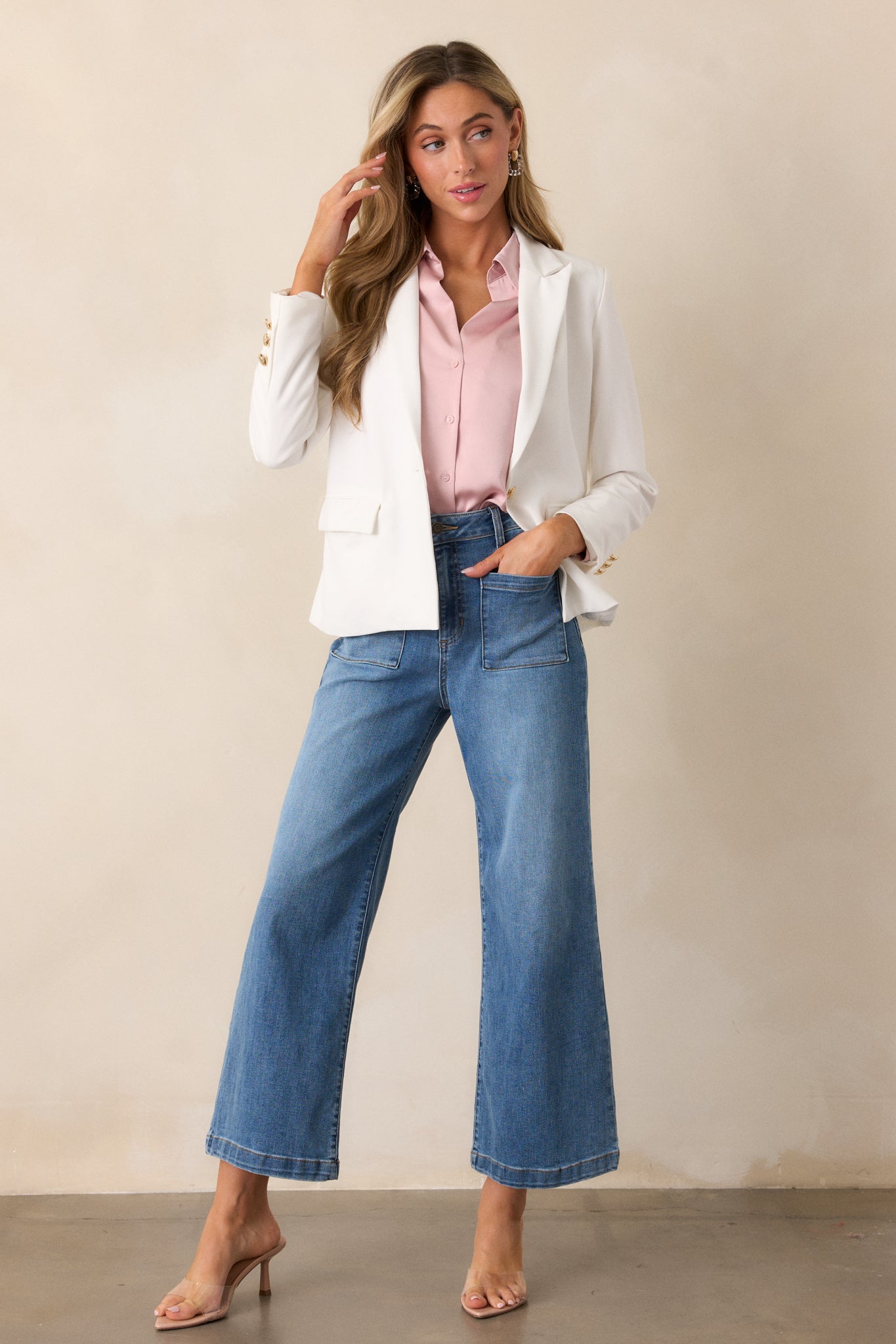 A full-length view of a white blazer featuring gold hardware, faux pockets, and a v-neck collar, styled with its sleek silhouette.