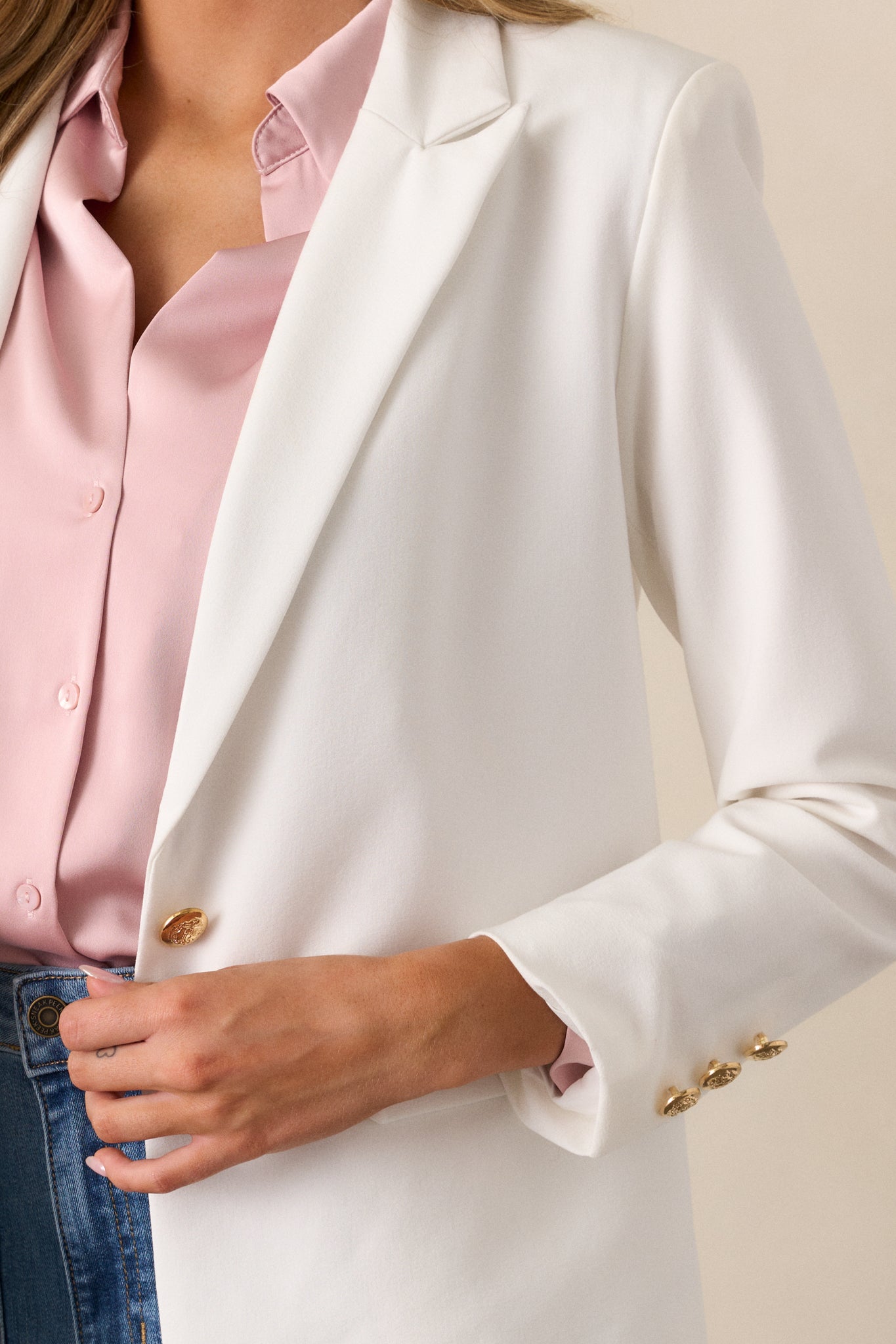 A close-up view of the white blazer's gold hardware, emphasizing its bold, luxurious detail.