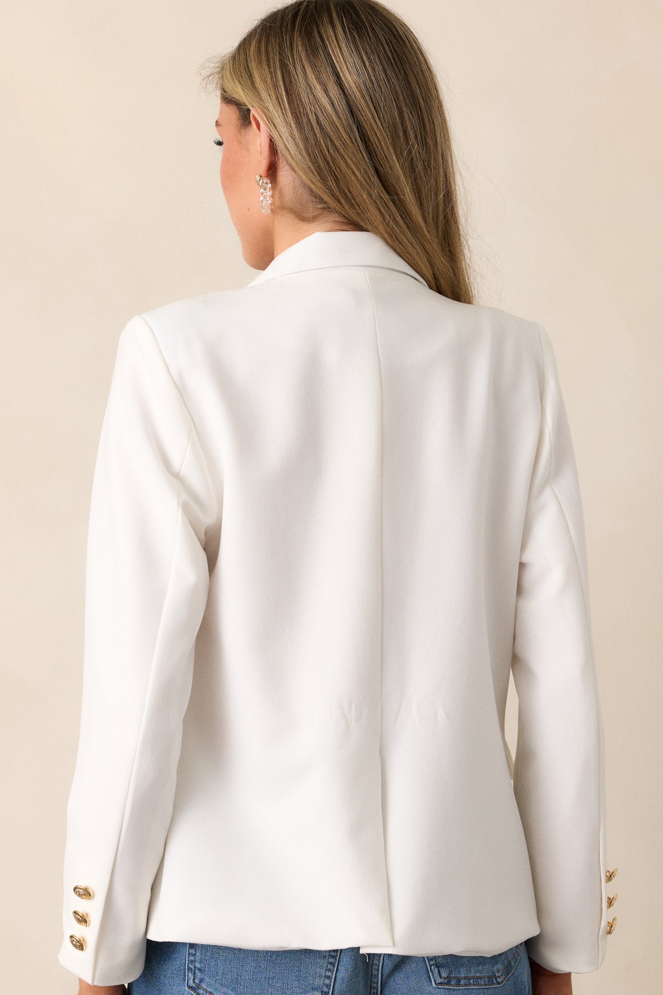 A back view of the white blazer, showcasing its seamless design and structured finish.