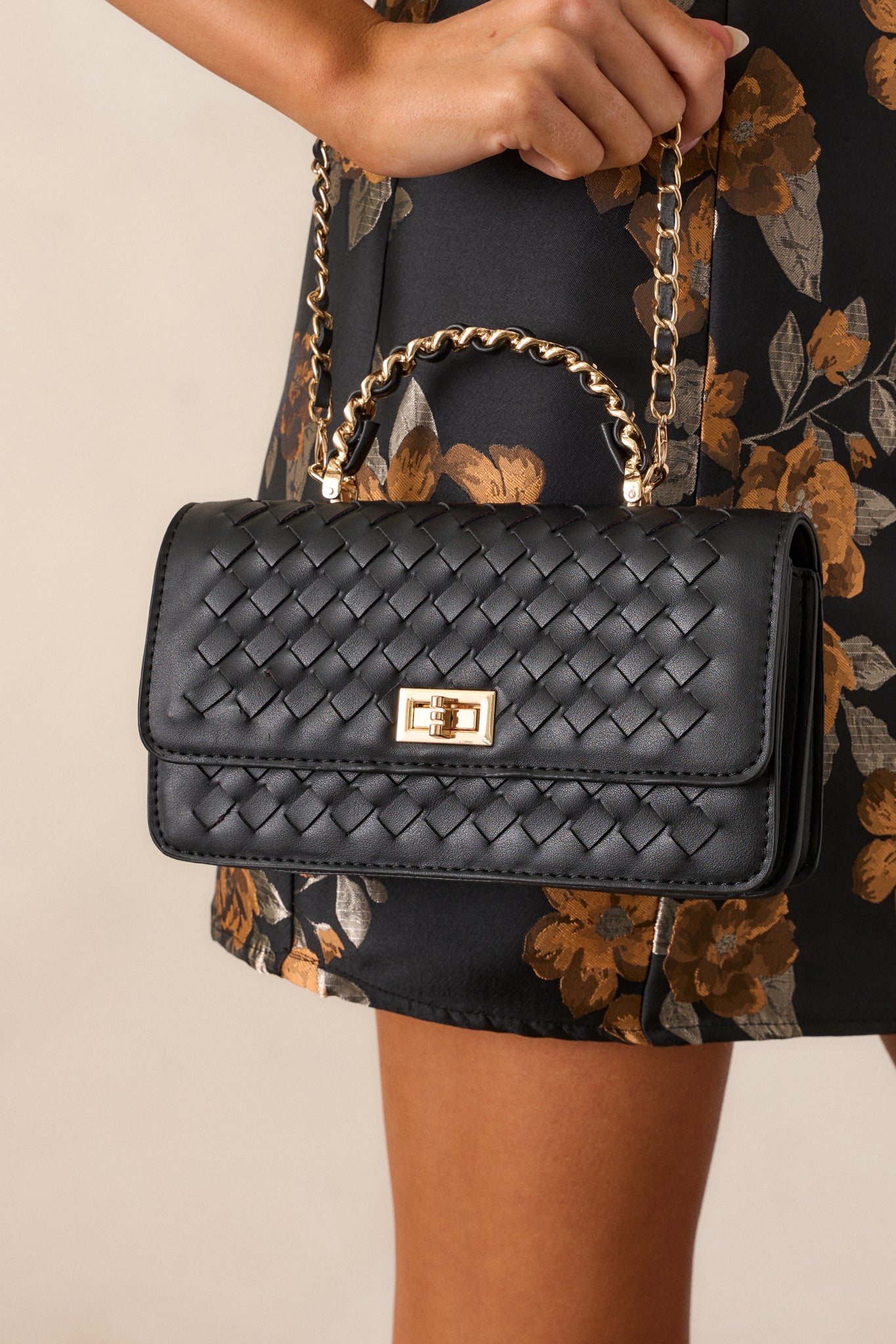 Side angle of the handbag, highlighting the woven texture, gold hardware, and the black and gold chain woven handle on top.