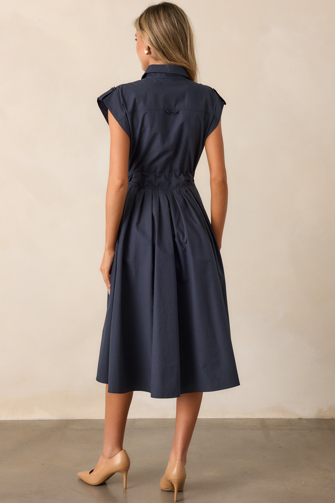 A back view of the navy dress, capturing the design of the self-tie belt at the back and the clean lines of the dress, with the cap sleeves completing the stylish look.