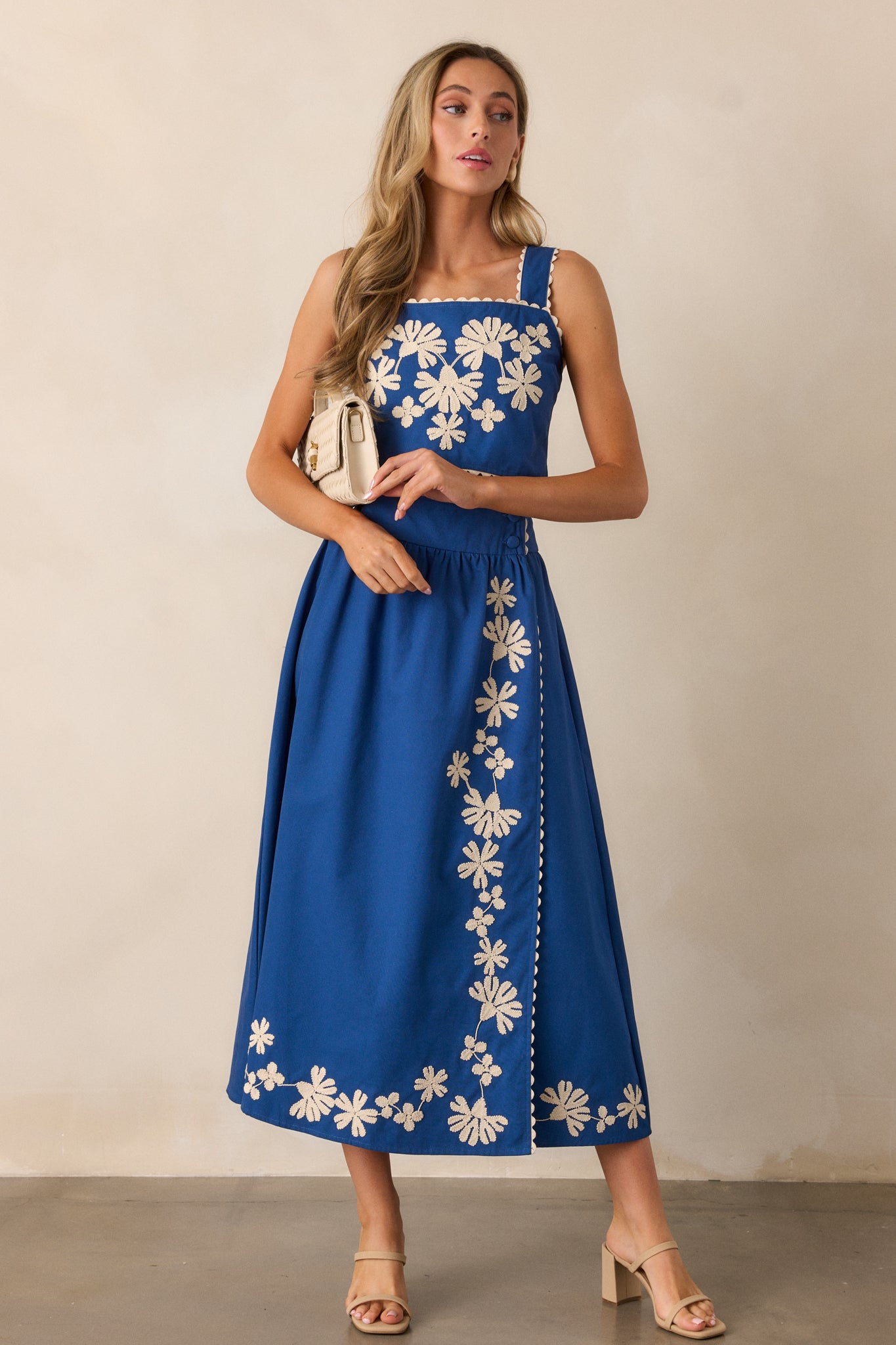 Full view of the blue skirt, showing the high-waisted fit with ivory floral embroidery and two functional waist buttons.