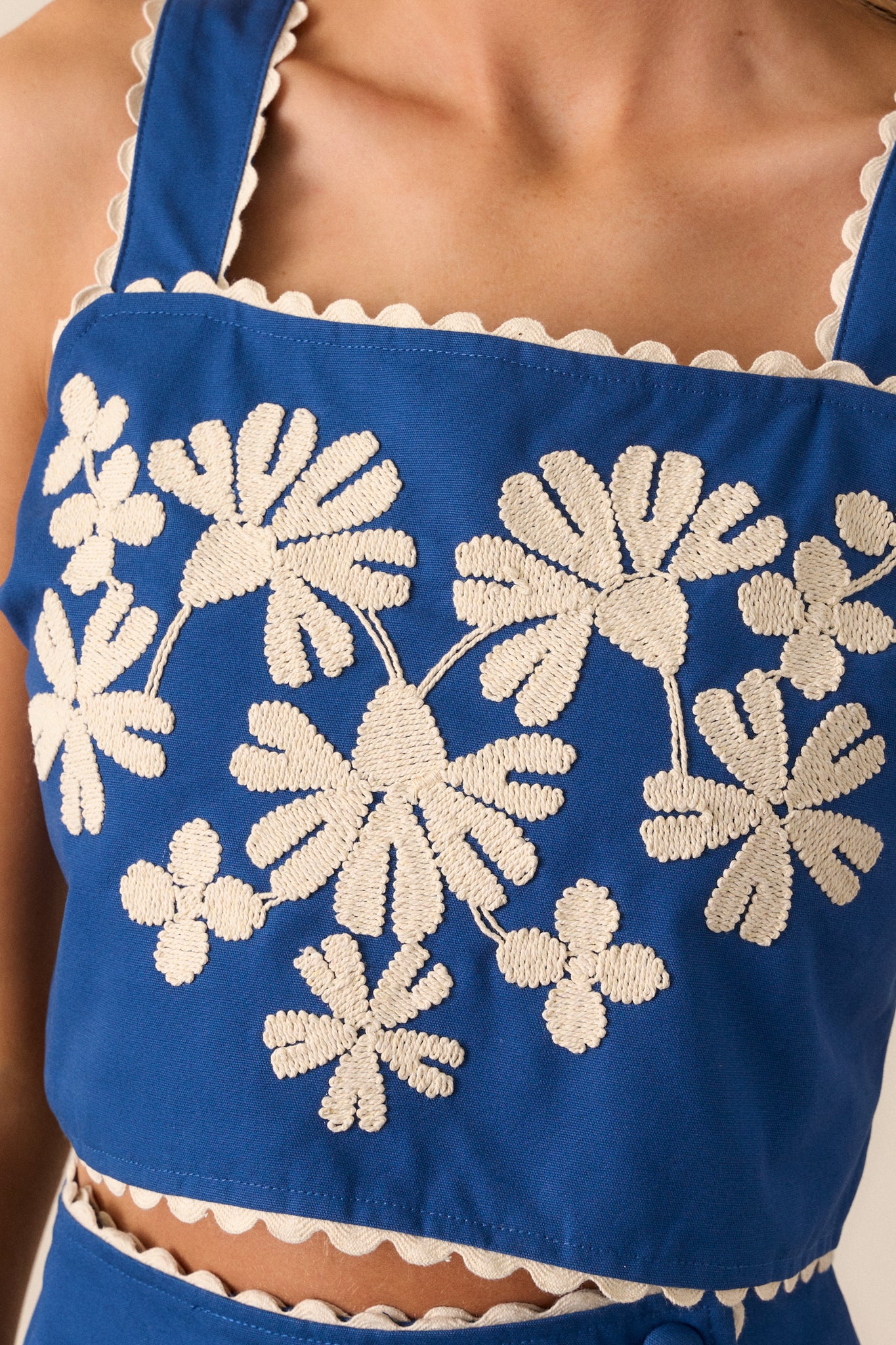 Extreme close-up of the embroidered floral design, emphasizing the texture and colors of the embroidery against the blue fabric.