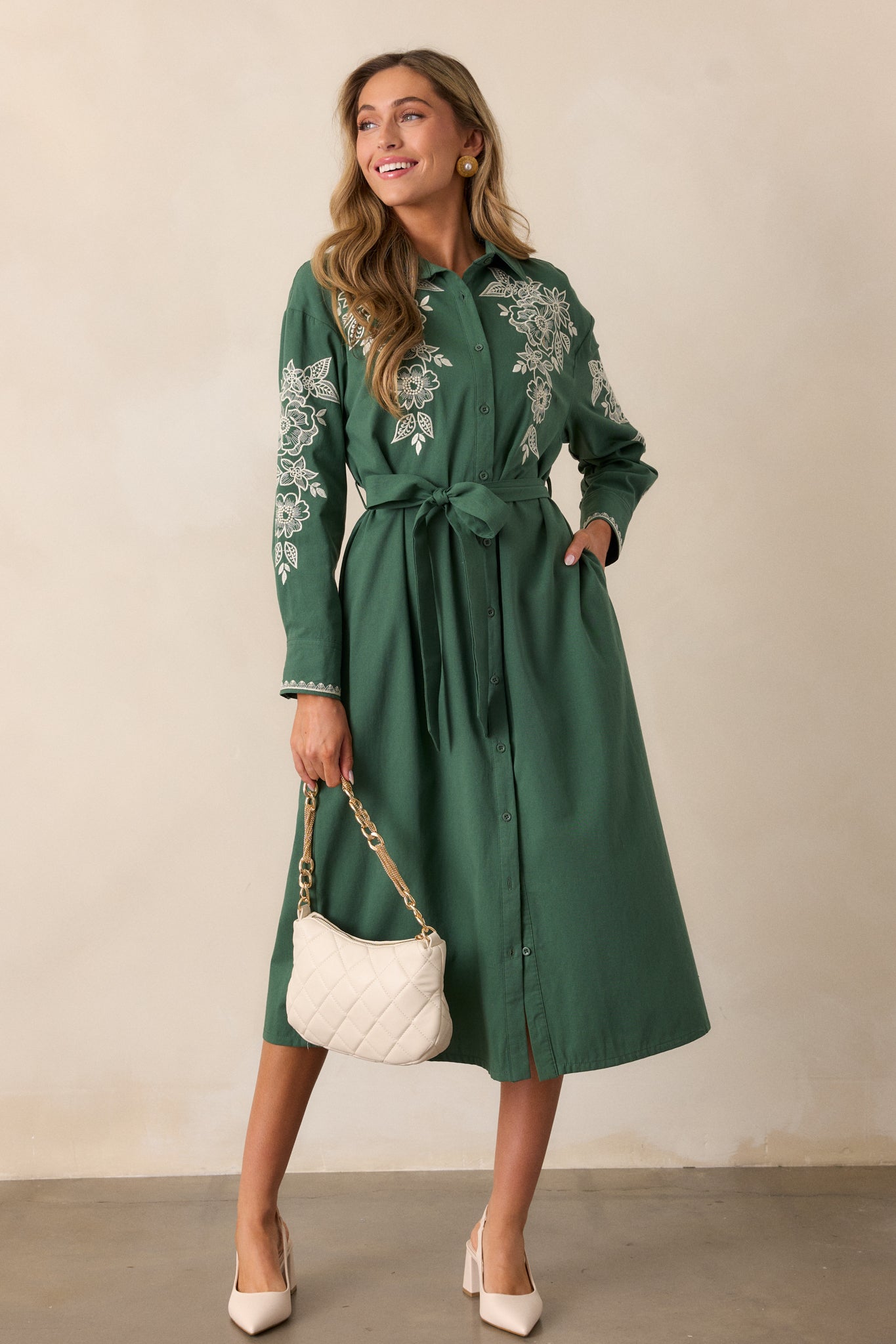 Side view of the dress, highlighting the floral embroidery on the chest and the relaxed fit of the long sleeves with buttoned cuffs.