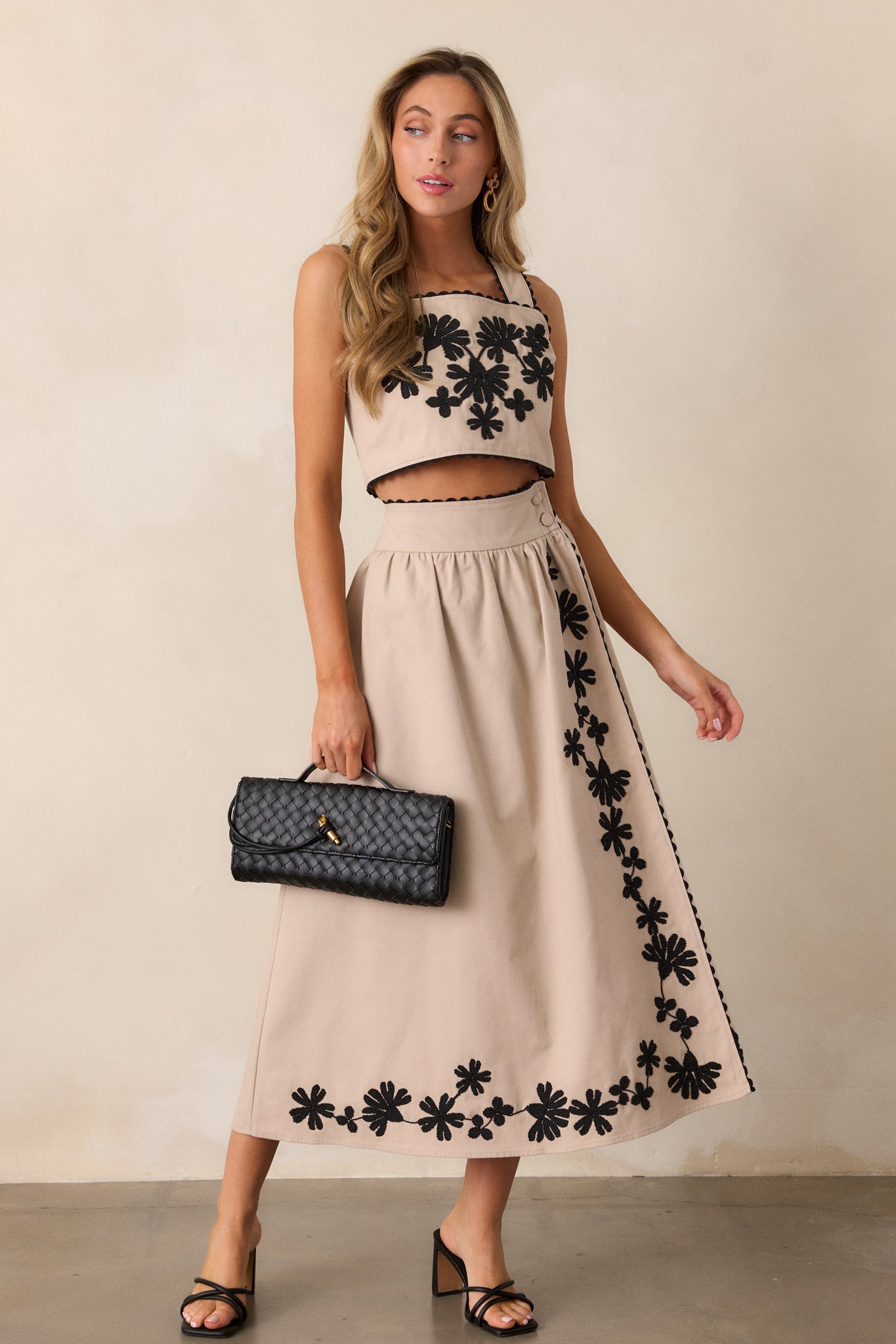 Full view of the taupe skirt, showing the high-waisted fit with black floral embroidery and two functional waist buttons.