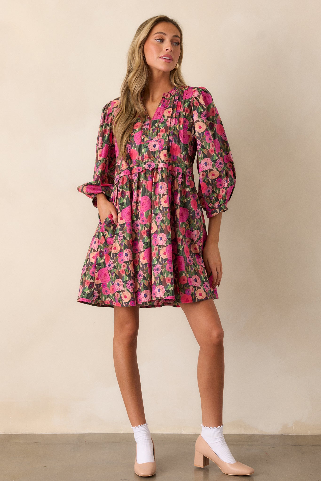 Front view of a pink mini dress with a pleated yoke, an a-line cut, and delicate floral pattern