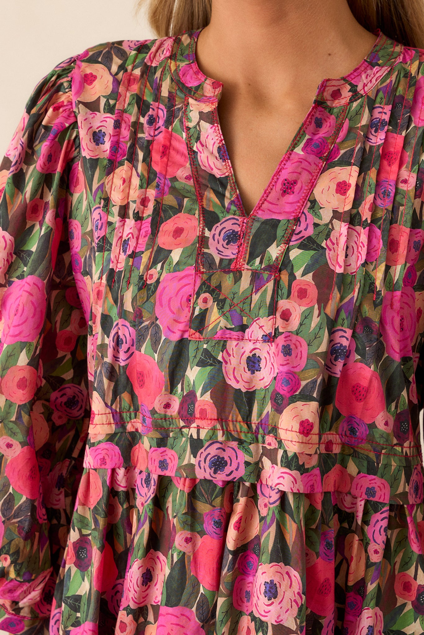 Detailed close-up of the pleated yoke and vibrant floral print on the pink mini dress.