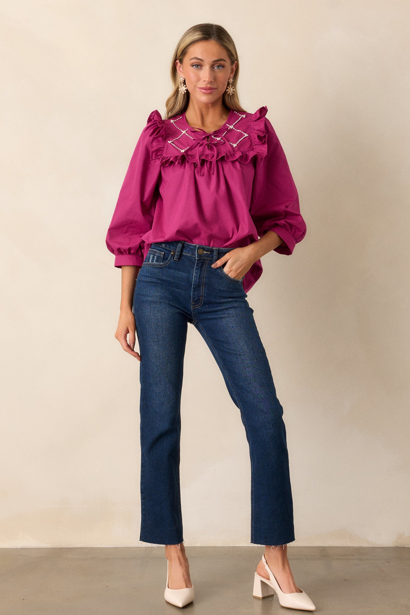 A dark fuchsia top showcasing a faux pearl lattice yoke with ruffle detailing, complemented by a keyhole neckline adorned with two self-tie bows.