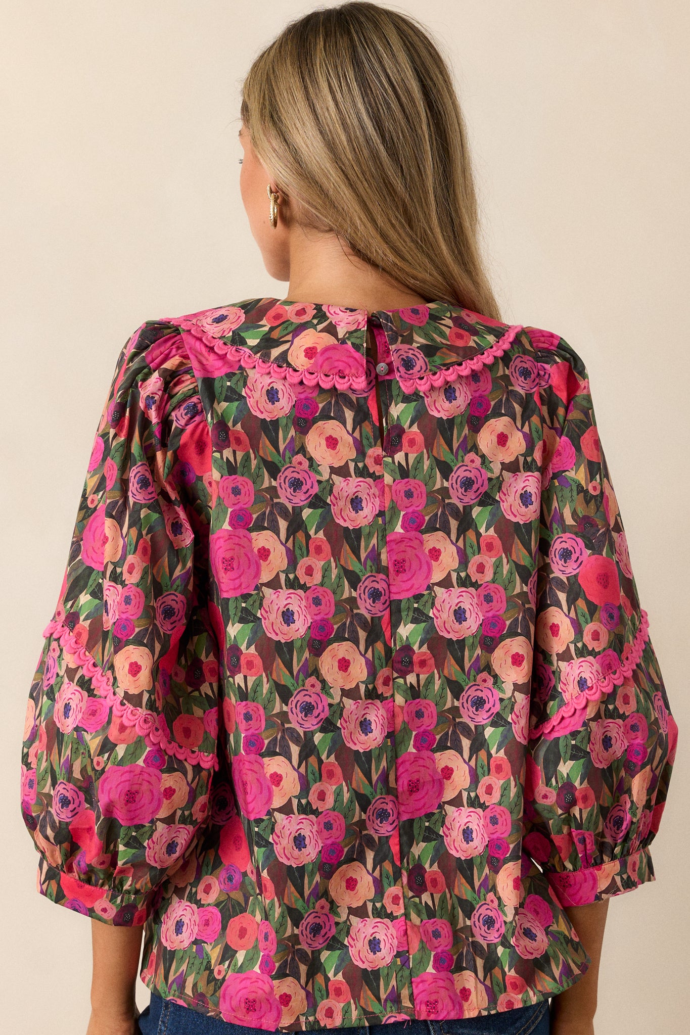 Back view of the pink blouse showing the relaxed fit and subtle floral pattern.