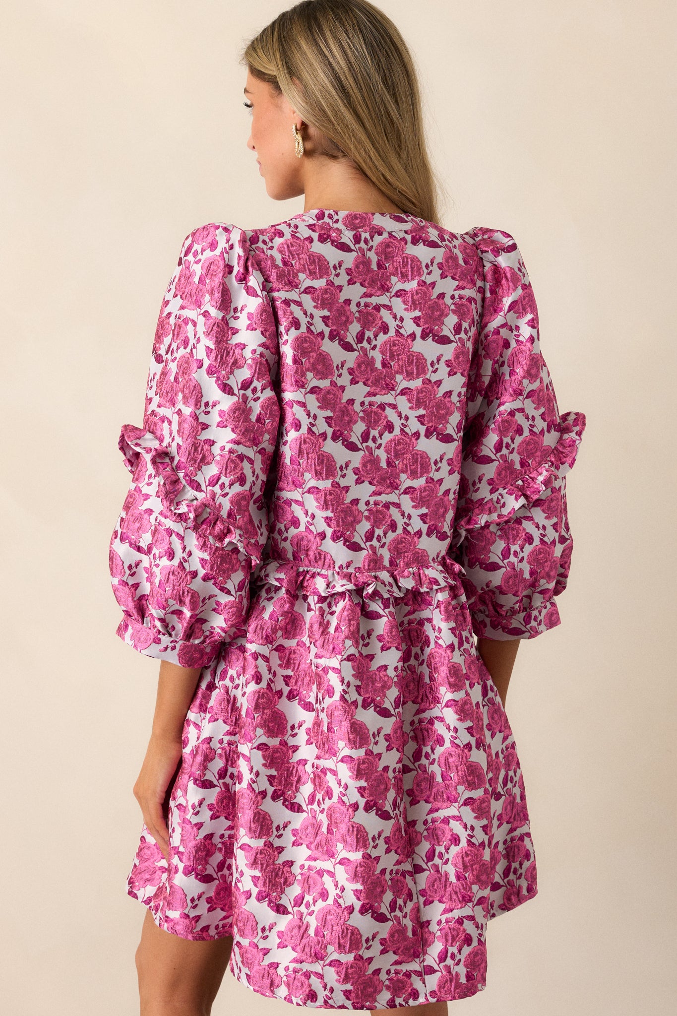 The back of the pink dress, featuring a smooth finish with ruffle detailing at the waist and elegant puff sleeves.