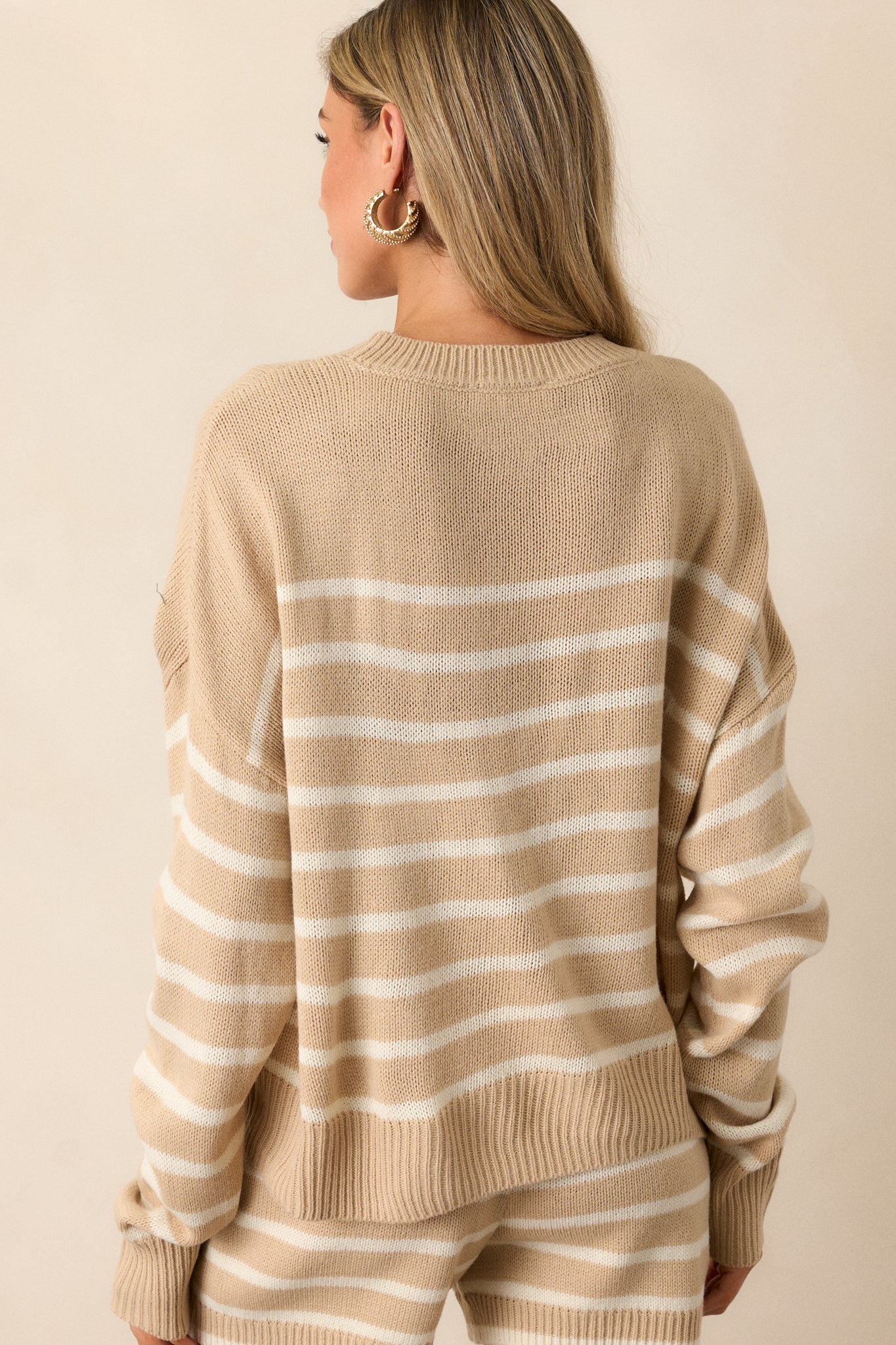 View of the back of the sweater, featuring the continuous horizontal stripe design and the clean ribbed hem for a polished look.