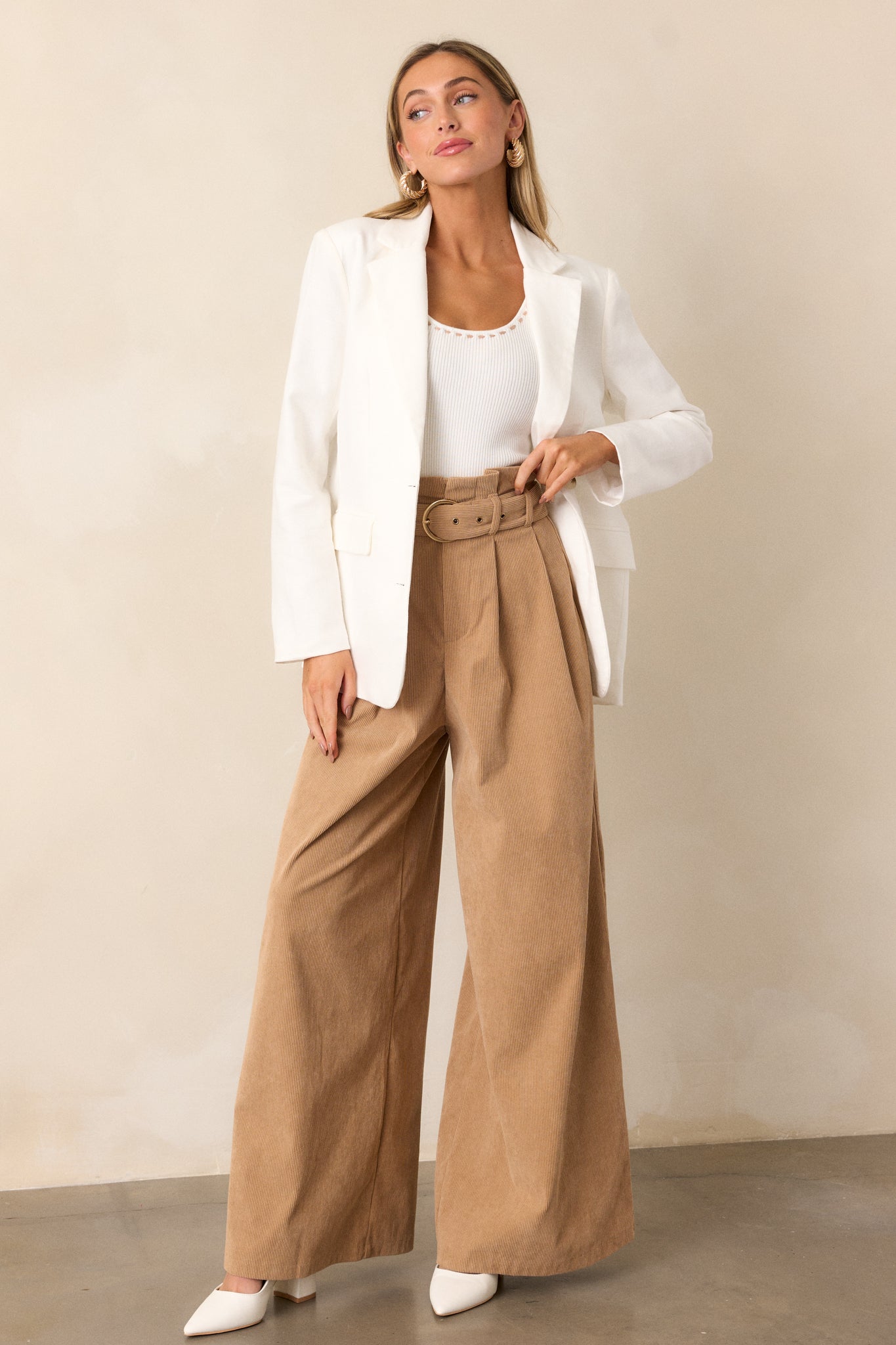 Full-length view of a model wearing the white blazer, emphasizing the collared neckline, functional half button front, padded shoulders, and long sleeves.