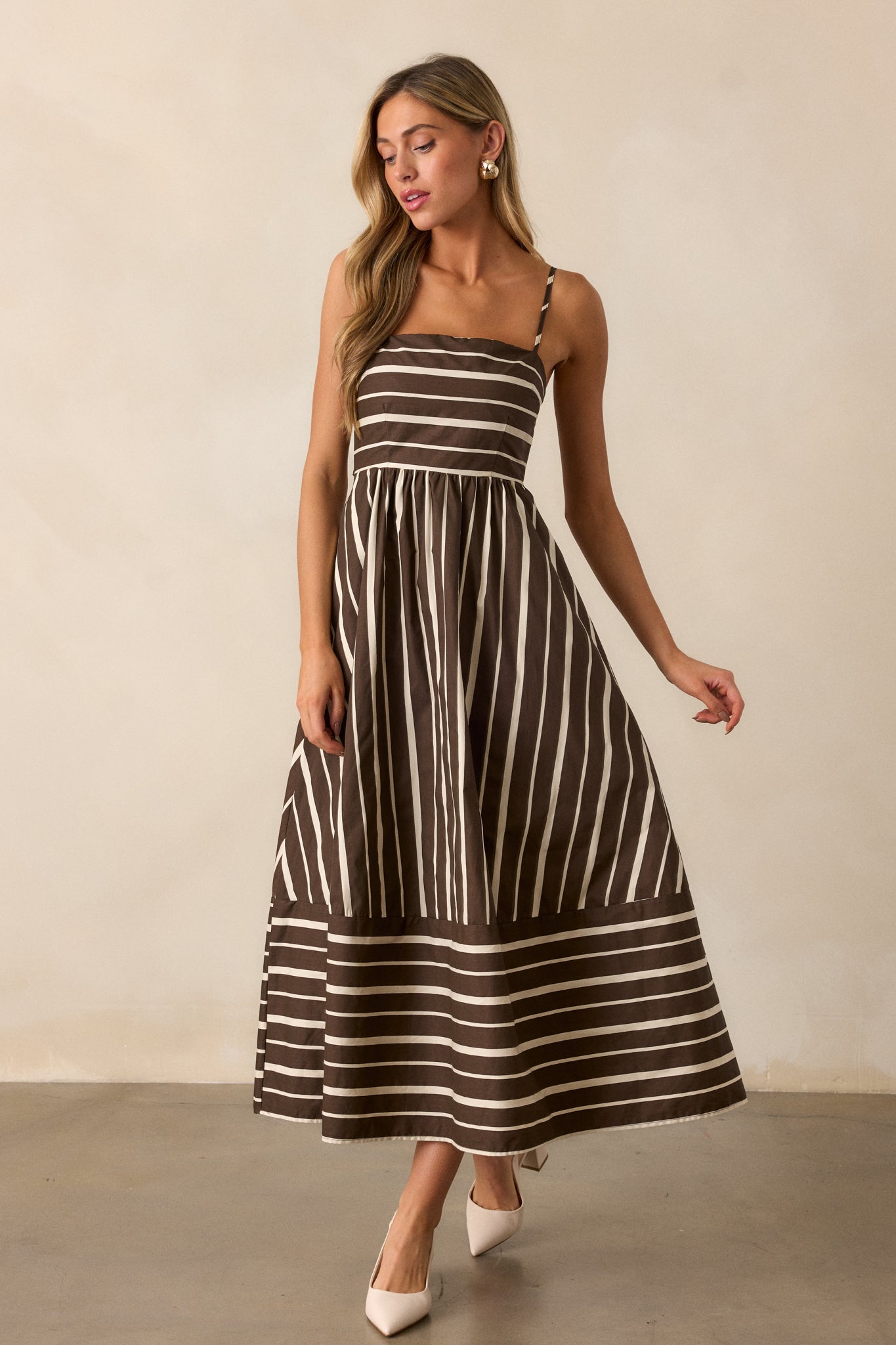 Angled view of the brown dress, emphasizing the movement of the fabric and the way the stripes create a playful, modern aesthetic.