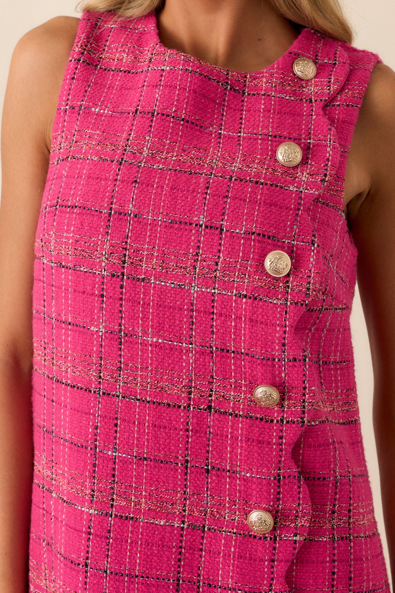 Close-up of the decorative gold-embellished buttons on the front of the pink dress, highlighting the intricate scalloped hem design.