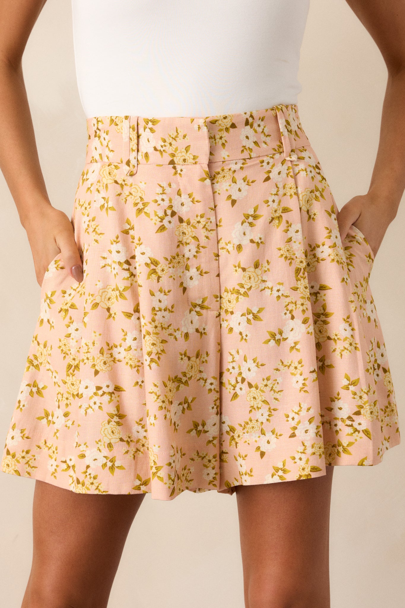 Close-up of the front of the peach shorts showcasing the zipper and clasp closure and belt loops.