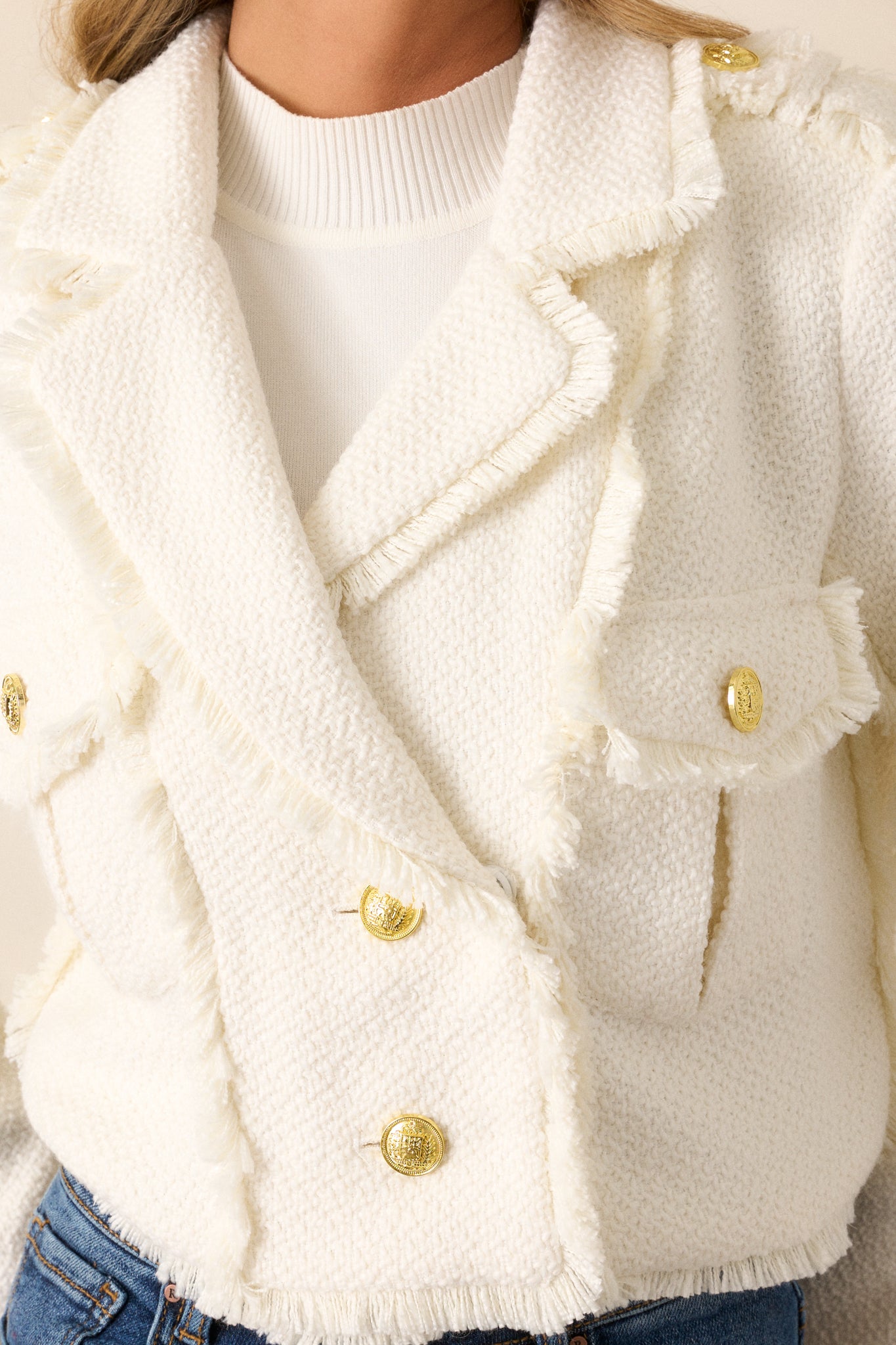 Extreme close-up of the gold button on the front, highlighting the texture of the fabric and the intricate button detailing.