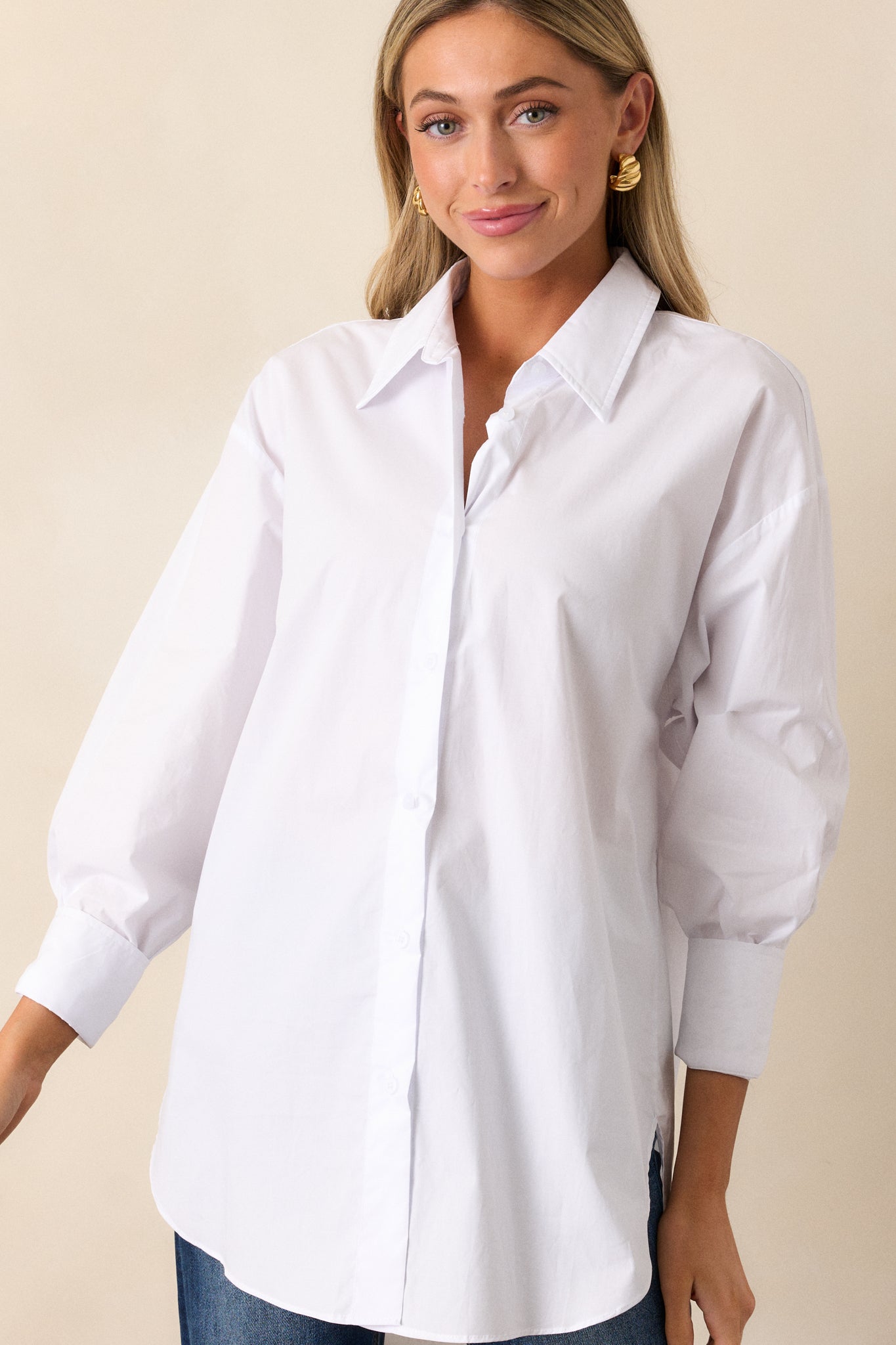 A complete look at the white top highlighting its relaxed fit, structured collar, and billowy sleeves in natural light.