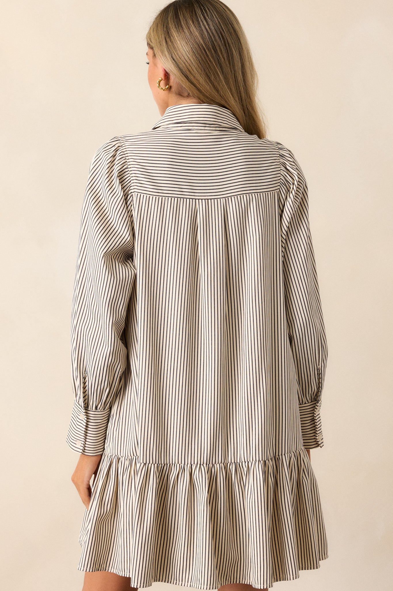 View of the back of the dress, featuring the mismatched stripe patterns and the clean, structured design of the drop waist tiers and long sleeves.