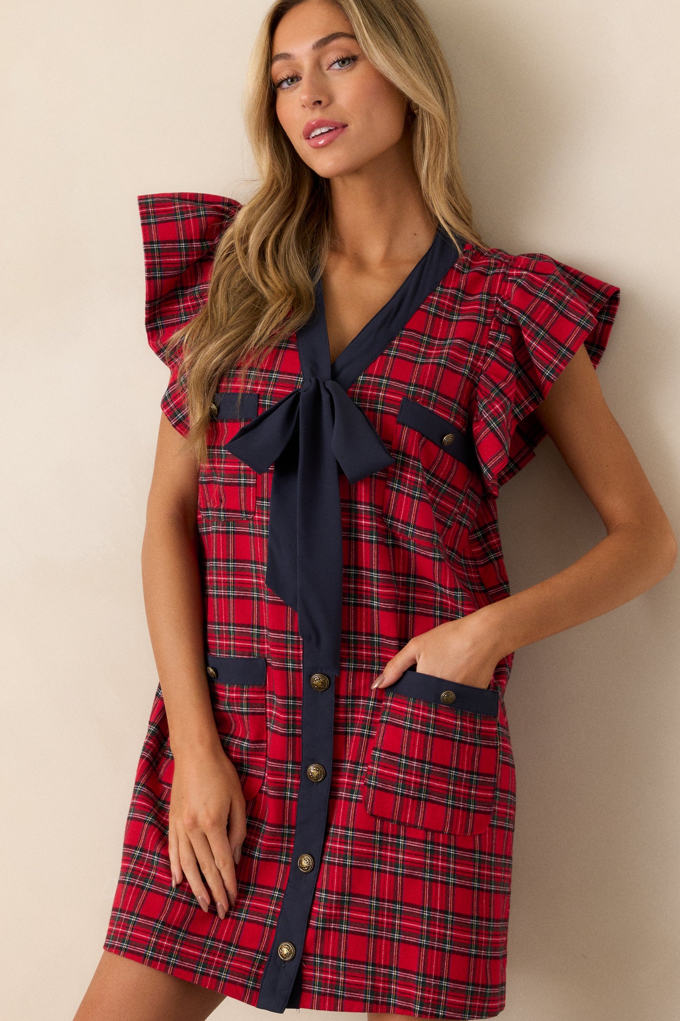 Zoomed-in view of the plaid mini dress’s functional front pockets, focusing on the red and navy plaid pattern and fabric texture.