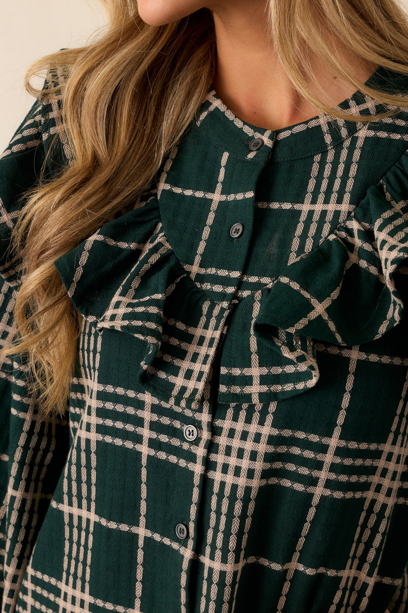 A detailed shot of the button front and ruffled yoke detailing, showing the precise stitching and the contrast between the green fabric and ivory plaid.